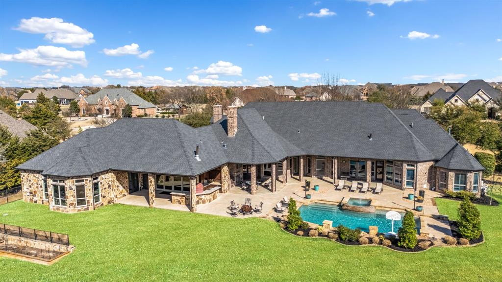 On 1.86 acres in an established ESTATE neighborhood, this custom home showcases exceptional craftsmanship, flexible living spaces, and resort-style outdoor amenities. Separate private staircases ensure easy access to the media and upstairs bedroom retreat while architectural details include tray ceilings, custom baseboards and trim, solid wood doors, and plantation shutters throughout. Up lighted tray ceilings in the family room, foyer, and primary suite create a refined ambiance, complemented by custom paint selections and designer finishes. The home offers 6 bedrooms, 6.5 baths, and an oversized 5 car garage. Also featured is a separate state of the art gym with full bathroom, accessible by the back patio. This unique space can easily be converted into a mother-in-law suite, office or bedroom if preferred. The gourmet kitchen features granite countertops, preparation space, top tier appliances and opens to the family room with a wood-burning fireplace. Designed for entertaining, the home includes a temperature-controlled wine cellar with wet bar, ice maker, and surround sound. The primary suite features a dual-sided gas fireplace and a flex space ideal for an office, nursery, sitting area, or expanded closet. The outdoor living shines with an extended covered patio featuring stained wood ceilings, ceiling fans, fireplace, and wood storage niches, kitchen area with a sink, refrigerator, grill, pizza oven, oversized pot burner perfect for crawfish boils, and extra storage. Additionally, the pool and spa feature a PebbleTec finish, slate stone landscaping, and gas lighting. Full exterior lighting and a comprehensive security system enhance ambiance and peace of mind. The property is fully fenced and backs to a creek and open space with no neighbors behind offering privacy and true ESTATE living in Prosper, TX. The home lives much like a single story with bonus space upstairs. Please access the gym from the back patio doors. Near Restaurants, Shopping, Highways.