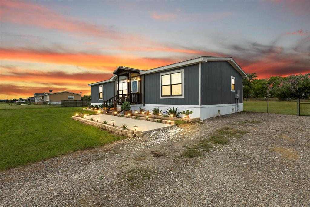 Built in 2022 and sitting on a full acre, this beautifully maintained 3-bedroom, 2-bath home offers the perfect blend of modern comfort and country charm. From the moment you arrive, you’ll notice the oversized recycled asphalt driveway, updated landscaping, and new fence with two gates providing both curb appeal and functionality. A recently added concrete walkway leads from the driveway to the front door, creating a warm and welcoming entrance. Inside, the entire home has been freshly repainted just two months ago, giving the space a bright, clean, move-in ready feel. Step outside and enjoy the spacious partially covered back deck, ideal for relaxing, entertaining, or enjoying peaceful Texas evenings. The property also features two storage sheds (10x14 and 12x16), offering plenty of room for tools, hobbies, or extra storage. With secondary access to the backyard from FM 148, this property provides added convenience and flexibility rarely found. Enjoy the space, privacy, and versatility of acre living while still being close to everything you need.
