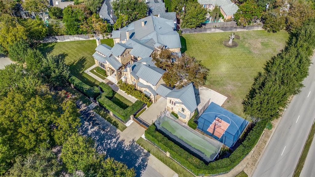 Located in the coveted Bluffview Inwood Terrace area, this exceptional estate, set on a one-acre lot, combines elegance, comfort, and timeless charm. The newly remodeled kitchen is a highlight, featuring stained wood cabinetry, quartz countertops, top-tier appliances, a large island with seating for eight and a convenient wet bar making entertaining a breeze! The great room boasts soaring ceilings, exposed beams, and large windows that overlook a covered deck with stone fireplace and views of the expansive lawn. On the first floor, you'll find a formal living room with fireplace, dining room with dry bar, study with fireplace, and a private guest bedroom. The primary suite offers a peaceful retreat with access to the outdoors, a renovated bath, and an expansive walk-in closet with custom built-ins. Upstairs, there are four spacious bedrooms, each with a designer bathroom, plus a media room, workout room with wet bar, and a massive playroom.  Old world style wine cellar with built in wood racks, bar area and half bathroom. Three stop elevator. A charming guest house behind a gated drive offers complete privacy, with a bedroom and ensuite bathroom, kitchen, and living area. The property also features a sport court, professional-grade batting pitching cage, and a large lawn for added seclusion. Located near Preston Hollow, Highland Park, SMU, Downtown Dallas and major airports, this home combines luxury, style, and convenience for the ultimate lifestyle.