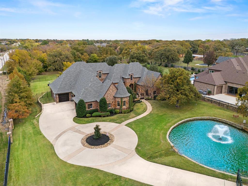 Spectacular gated estate on 1.6+ ACRES features an attached guest quarters, a private pond & backyard oasis, a charming courtyard, and a 4-car garage! Established neighborhood, mature trees, & outstanding location -- minutes to 377, 114, I35, with quick access to downtown Fort Worth, DFW Airport, local shops & dining. Designed for family living & entertaining, this stunning estate combines elegance and functionality with soaring ceilings, hand-scraped hardwood floors, plantation shutters, exposed beams, striking stone fireplace, music system throughout the estate, custom cabinetry with built-ins, moldings & millwork throughout. The formal dining showcases travertine and hand scraped hardwood floors, wrought iron and crystal chandelier, and French doors leading to the outside courtyard. A well-appointed kitchen features two islands, stainless steel appliances, and modern updates that opens to an adjacent breakfast nook. Retreat to the exquisite primary suite that includes a cozy turret seating area, while the luxurious en-suite bath offers a steam shower, dual toilets, a jetted tub, and a massive closet with a washer-dryer hookup.

The main floor also includes a large office, a secondary office, and three bedrooms with 3.5 baths, providing ample space for comfort and storage. Upstairs, you'll find a theatre room, a workout room or flex space, an additional bedroom, and a full bath. The backyard oasis begins with a covered outdoor patio and fully equipped kitchen with a fabulous brick & stone fireplace that opens to an extended patio with a sparkling pool, a relaxing hot tub and water features. Crisp flower beds & landscaping for all seasons with an extensive, fully-fenced backyard, mini golf course, and space for pets and play. In addition, the attached guest quarters feature a kitchenette, a full guest bath & walk-in closet, with access to the courtyard -- the perfect space for in-law visits! Full house generator. Jellyfish Lighting for all seasons. NO HOA!