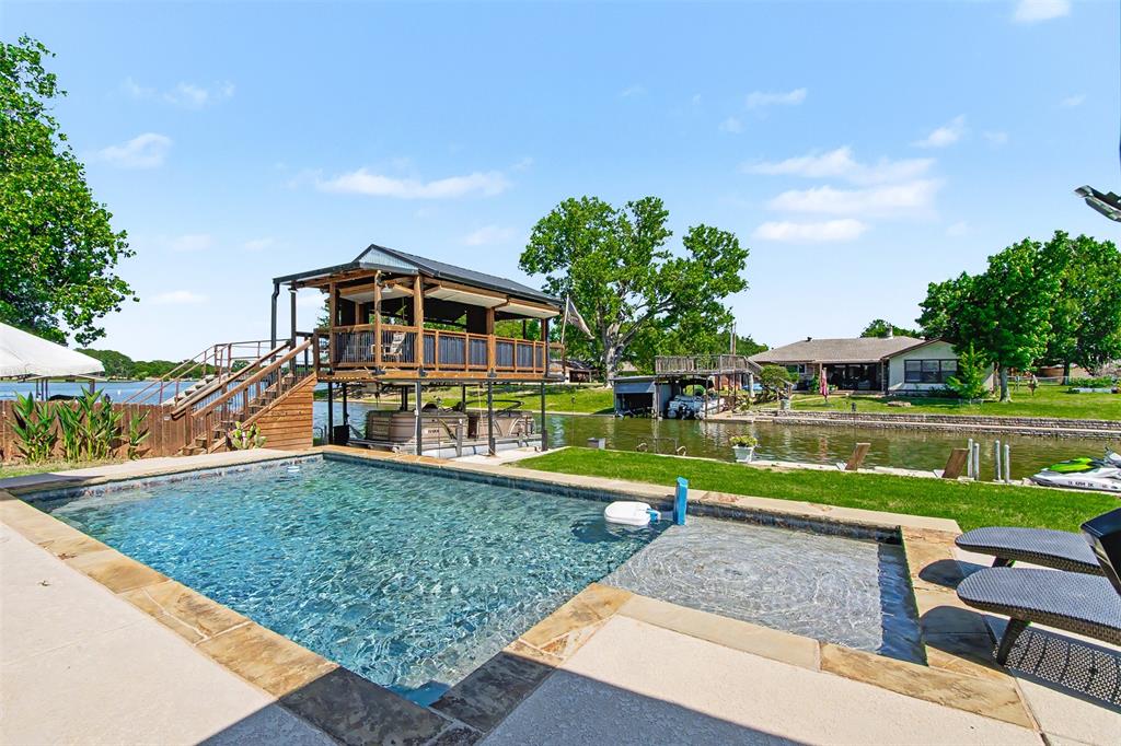 PRICED TO SELL & NO HOA! Exceptional Lake Granbury waterfront property offering the perfect blend of luxury, recreation, and investment potential. This beautifully maintained home features an open concept floor plan, spacious living areas, a freshly coated 2-car garage, and stunning lake views throughout.
Step outside to your private backyard oasis complete with a sparkling pool, covered lakeside patio, and fully equipped outdoor kitchen featuring a serving bar, sink, griddle, and pizza oven perfect for entertaining family and friends. The impressive boathouse is a standout feature, offering a bar area, pulley windows, waterfront seating, and panoramic views of the lake. Whether you're hosting game day gatherings, enjoying sunset cocktails, or simply relaxing by the water, this space is designed to impress.
The expansive living room opens through French doors to the covered outdoor living area, seamlessly blending indoor and outdoor living. Enjoy direct access to Lake Granbury from your private waterfront retreat. Additional items included with an acceptable offer include a gas-powered golf cart, custom couch, pool table, and SeaDoo. Boat may be negotiable separately.
Ideal as a primary residence, vacation home, or short term rental investment opportunity. Located in a desirable lakeside neighborhood with no HOA restrictions. Rarely does a property offering this level of waterfront enjoyment, entertaining space, and flexibility come to market.
Schedule your private showing today and experience lake living at its finest.
Headliner
NO HOA! Stunning Lakefront Retreat with Pool & Incredible Boathouse
Lake Granbury Waterfront Oasis with Pool, Outdoor Kitchen & Boathouse
Exceptional Waterfront Living, Pool, Outdoor Kitchen, No HOA
Turn-Key Lakefront Entertainer's Dream on Lake Granbury
Luxury Lakefront Living with Resort-Style Amenities & No HOA