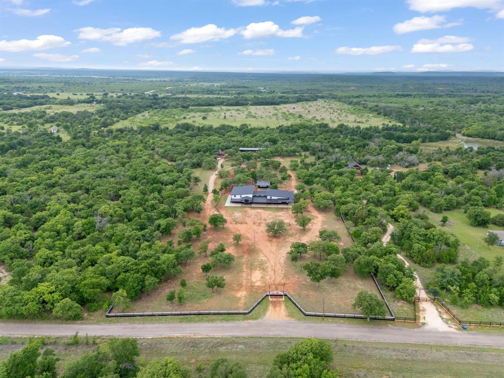 Escape to the country on 6.186 acres in Stephenville, TX, featuring scattered mature trees, a gated entrance, and full pipe fencing, perfect for horses or livestock with a covered barn for storing hay and room to add multiple horse stalls!  This meticulously designed 4 bedroom home offers tile floors throughout the lower level with the primary suite, laundry room and half bath downstairs and three additional bedrooms and a full bath upstairs as well as a flex space for a second living area or game room! Enjoy beautiful sunrises or sunsets and breathtaking views for miles from the second story covered back deck or the front balcony.  The 1437sf attached garage is connected by a breezeway and offers incredible versatility featuring over 550sf of guest living quarters offering 2 bedrooms and a full bath upstairs, plus a half bath and laundry room below. The pull through garage provides ample space for boats, RVs, multiple vehicles, or even a game room style set up.  Step outside to a covered porch off the back of the home with two restrooms already started, creating the perfect foundation for a future outdoor entertaining space or pool area. A rare blend of functionality, space, and scenic country living just minutes from Stephenville and in Morgan Mill ISD!