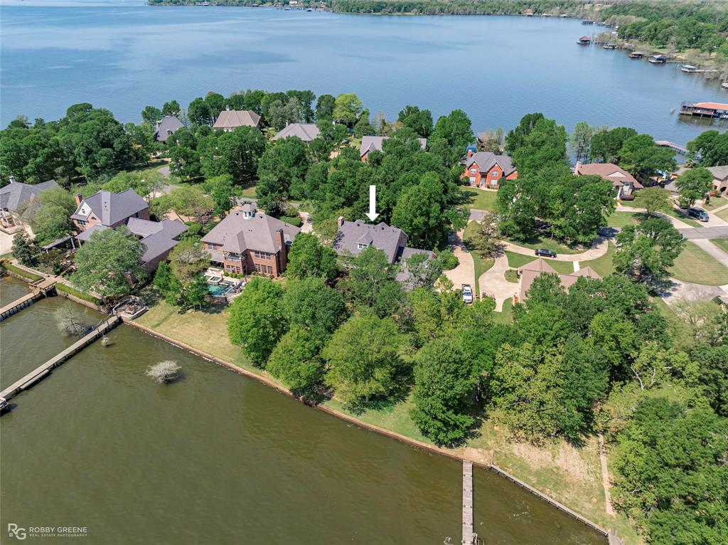 Absolutely stunning home available in gated Squirrel Point on Cross Lake with plenty of space for entertaining both inside and out! As you step inside the front foyer, the large formal dining room sits immediately to your right while the spacious living room with floor-to-ceiling windows overlooking the lake beckons you forward. Complete with custom built-ins and a cozy fireplace, the living room flows seamlessly into the kitchen and hearth room. Meal prep will be a breeze in the modern kitchen, boasting abundant cabinet space, a center island, and stainless appliances. From the hearth room, French doors lead into the sunroom, giving you even more flexibility for entertaining. A dedicated office ensures you'll have a quiet space to work with more views of the lake. The relaxing primary suite includes a spacious ensuite bath with dual vanities, jetted tub, and separate shower. The additional two bedrooms have their own ensuite full bath, ensuring convenience and privacy for guests or family. The bonus room upstairs with adjoining half bath offers flexibility to use as a media space, game room, or hobby room. 1700sf floored attic space ensures you've got plenty of room for storage! Outside, the extended back patio is perfect for hosting BBQs or just spending quiet time outside. The backyard also features a stone firepit area and plenty of room for a garden. Don't miss your opportunity to own this little slice of heaven and schedule your private tour today!