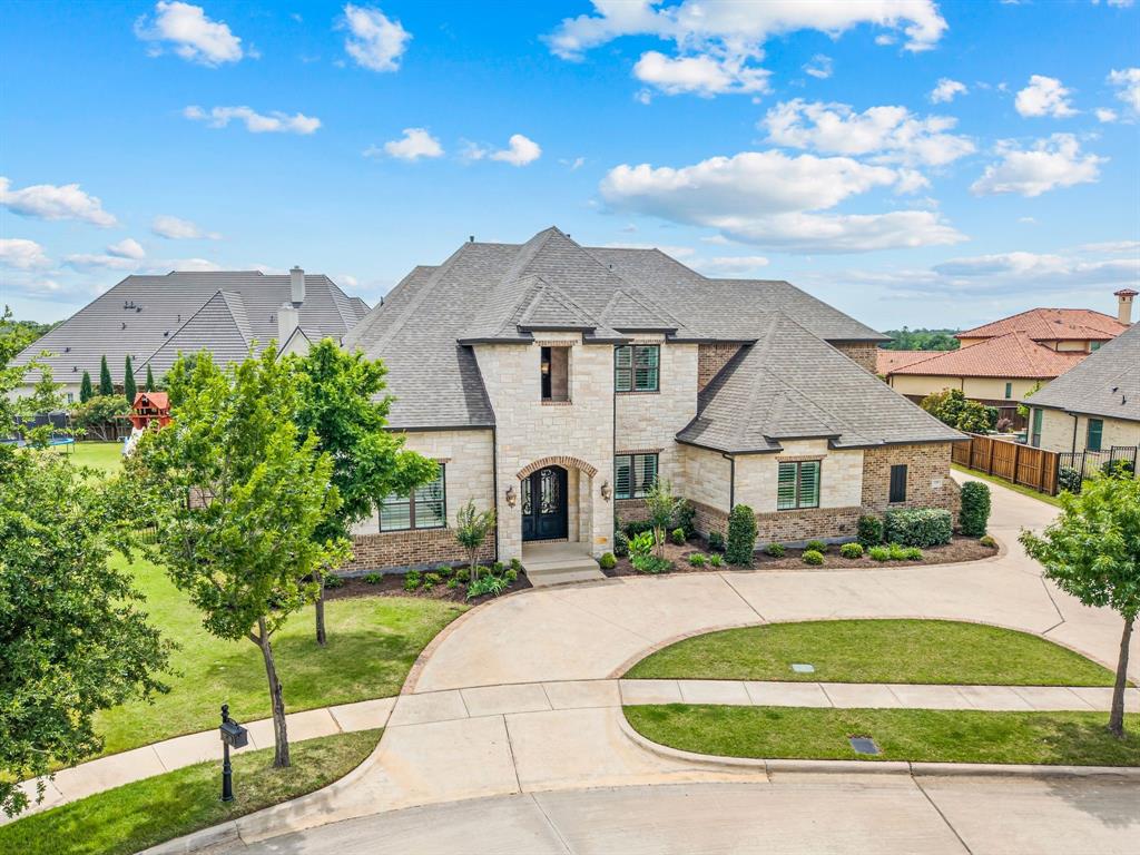 There is a particular feeling that comes with a home where every decision was made with intention and nothing was left to default. Where the details that most builders treat as afterthoughts are the ones that stop you in a room. That is the feeling of 1109 Savoy Lane.
The iron door opens and the home receives you. A curved staircase rises through the foyer, a chandelier suspended above it, hardwoods running long and warm toward the back of the house where a wall of steel-frame windows holds the whole of the yard in view. It is the kind of arrival that makes you slow down without being told to.
The great room and kitchen share that light and that outlook. A floor-to-ceiling limestone fireplace anchors one end. The kitchen anchors the other: cabinetry to the ceiling, an island generous enough to become the center of any gathering, professional appliances, a dry bar, and a breakfast room that lets the morning come in quietly. The whole of the main living wing moves as one graceful, unhurried whole.
The owner's suite is its own world within the home. Main level, privately positioned, windows facing the yard, a spa bath beyond, and a walk-in closet that connects directly to the laundry room because someone thought carefully about how mornings actually work. A guest suite, a dedicated office, and a media room complete the downstairs. Upstairs, a generous gameroom and three additional bedrooms, each with its own private bath.
More than half an acre. A covered patio with remote-controlled screens opening to a backyard that stretches farther than most in Southlake. A four-car garage running 26 feet deep, insulated, wired for whatever you need it to be. Built in 2017. 5,648 square feet. Carroll ISD.