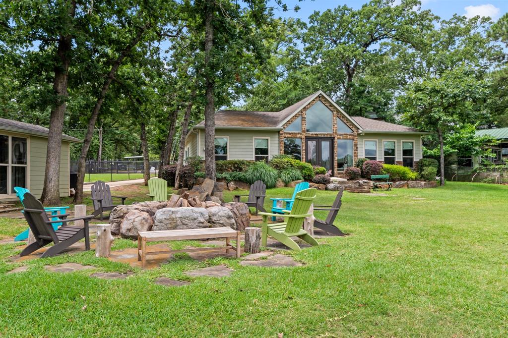 Furnished private gated waterfront home with guest house situated on approximately 175 feet of shoreline in a protected cove with an impressive 11 feet of water at the end of the dock when the lake is at full pool. Complete with a new vinyl retaining wall, this exceptional property offers the ultimate lakefront lifestyle. One of the property's most impressive features is the custom boathouse. It features a rebuilt 23 foot boat lift, 2 PWC slips, and a spacious covered lounge area equipped with a TV, stereo system, outdoor speakers, ceiling fans, refrigerator, ice maker, bar area and propane gas firepit . Anglers will appreciate the 10 removable fishing hatches and 30 artificial trees beneath the dock designed to attract fish. The large party deck has new decking and an oversized storage room that could easily be transformed into a bunk room, game room, or additional recreational space. Inside, the 3 bedroom 2 bath home offers 1,813 sq. ft of beautifully updated living space with luxury vinyl plank flooring throughout, expansive windows up to the vaulted ceiling with exposed wood beams, and linear electric fireplace. The kitchen is beautifully appointed with custom wood cabinetry, quartz countertops and backsplash, and a reverse osmosis drinking water system. Guests will enjoy their own private accommodations in the detached 300 sq.ft. guest house, complete with a full bath, kitchenette, mini-split HVAC system, and separate septic system. Additional amenities include a storage shed, and a large fire pit surrounded by eight Polywood Adirondack chairs. The 1,200-square-foot (30x40) metal pole barn located on Ruth's Hideaway Cove Lot B is available for purchase with the home for an additional $150,000. The barn includes a insulated workshop with mini-split HVAC system, water hook up for sink, and a 12x40 garden. The metal building and lot offer excellent flexibility and can be utilized as a garage, workshop, boat storage, or additional guest parking.
