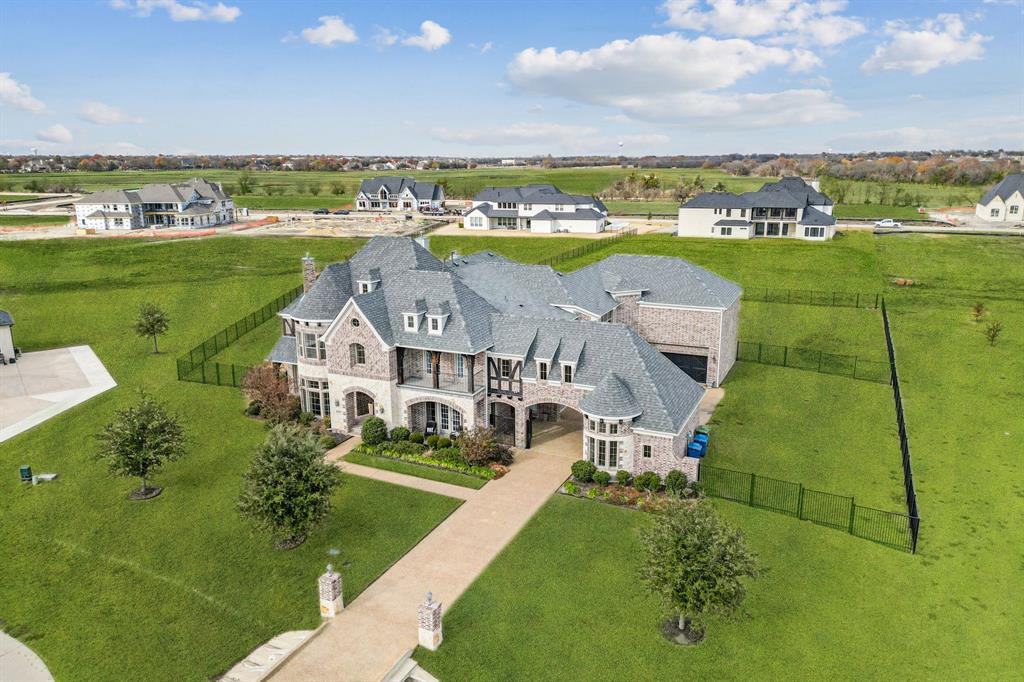 Exceptional Grand Home on over an acre in one of Parker’s most peaceful and picturesque neighborhoods. Designed with eye-catching details and accommodating spaces ideal for both entertaining and relaxing downtime at home, this expansive residence offers refined interiors, resort-style outdoor living, and the kind of space and freedom that’s hard to find. A dramatic double staircase sets the tone upon entry, framed by soaring ceilings, wood flooring, and elegant architectural detail throughout. At the heart of the home, a stylish kitchen centers around a 10-foot island with stainless steel appliances, butler’s pantry, and wine room perfectly positioned for hosting or day-to-day ease. The floor plan is as functional as it is impressive, with formal living and dining, an executive office, generous storage, and three separate staircases offering private access to each wing. A guest suite on the main level provides privacy and comfort for overnight guests, while every bedroom features walk-in closets and ensuite or adjacent baths. The primary retreat offers spa-inspired touches, including a jetted tub, frameless glass shower, and fireplace. Upstairs, enjoy a game room, media room, Juliet balcony, and both front and rear outdoor terraces offering scenic views of the lot and neighborhood. Downstairs, a rear porch with retractable electric screens leads to a backyard oasis, complete with a heated pool and spa, travertine decking, and a full outdoor kitchen with built-in grill, flattop, sink, and refrigerator. The screens on the covered patio and a fourth fireplace add year-round comfort. Additional upgrades include a brand-new roof and gutters, electric shades, a sprinkler system, security cameras, and a drive-through gated porte-cochere. This is luxury living with abundant space and freedom just minutes from Southfork Ranch, desirable schools, and convenient access to local amenities, yet quietly removed from the city's hustle.