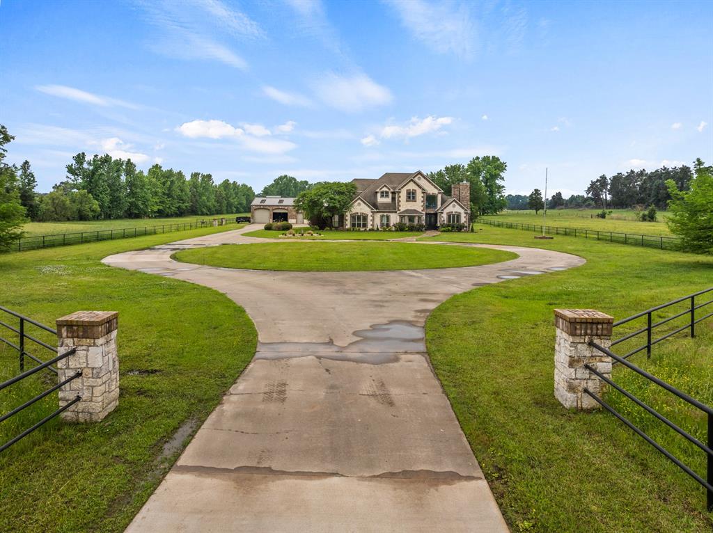 Welcome to your private East Texas estate—where luxury, space, and peaceful country living come together on 24.984 gated acres just minutes from town. This stunning 5-bedroom, 3-bathroom home offers over 4,100 square feet of thoughtfully designed living space, featuring soaring ceilings, rich finishes and an effortless flow perfect for both everyday living and entertaining. The heart of the home is a beautifully appointed kitchen with custom cabinetry, expansive countertops, gas range, and bar seating—all opening to spacious living and dining areas filled with natural light. From the elegant formal spaces to the cozy living areas, every detail has been carefully curated to feel both refined and inviting. The primary suite is a true retreat, complete with a spa-like feel and ample space to unwind. Additional bedrooms provide flexibility for guests, office space, or hobbies. Step outside and experience your own backyard oasis—featuring a resort-style pool with waterfall, spa, and a covered patio with fireplace and outdoor TV, perfect for year-round entertaining. The gated entrance and long private drive set the tone for the privacy and exclusivity this property offers. For those needing extra space, the property includes a large shop and plenty of room to roam, making it ideal for hobbyists, outdoor lovers, or anyone craving wide-open space. Located in Pittsburg ISD, this one-of-a-kind property blends upscale living with the tranquility of the countryside—without sacrificing convenience.