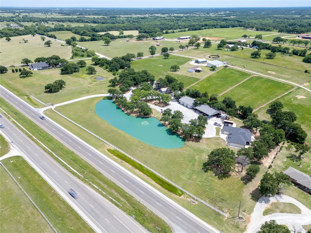 Exceptional custom estate on 5.48 acres offering picturesque views of the scenic pond with fountain, custom home, 2 shops, 6 car space carport, a private guest home, RV Hookups and storm shelter. Perfect property to live, work and entertain in one place. Well-designed custom home featuring 3 bedrooms, 2.5 baths, a two car garage, open living space, chefs kitchen and office. Stunning Chefs kitchen showcasing custom cabinetry, granite island, ambient above and under cabinet lighting with sleek modern light fixtures.  Serene primary suite with tray ceilings, recessed lighting paired with a spa like bathroom offering a walk in shower, relaxing garden tub and spacious closet. Expansive open-concept living space flowing effortlessly into the formal dining area, ideal for gatherings and entertaining. Office with built in desk, upper and lower cabinetry. Utility room with upper and lower cabinets and a full size washer and dryer area. Beautiful wood flooring, granite counters and modern light fixtures throughout. Beautiful, renovated guest suite with one bedroom, one bath, kitchen, dining, office and utility room. 40X60 Insulated Shop with 6 inch concrete floors and three garage doors. 40X60 Carport. 24X24 Insulated Shop. 8 person Storm Shelter. RV hookups including 30,40 and 50 amp connections. 3 separate electric meters and 2 septic's. One of kind property, completely fenced and gated. Easy commute to the DFW Airport. Close by shopping and restaurants. Whitesboro ISD or Choice of school.
