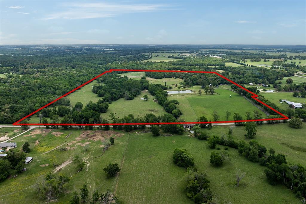Breathtakingly beautiful, this approximately 86 acre ranch offers a rare opportunity to own a serene and functional slice of countryside. Enter through the electric gated entry and stately board fencing, then follow the winding drive into peaceful country living. The property features five ponds, an active creek with low cattle crossings, and a 20+ acre hay meadow producing upwards of 100 rolls per year. Lush pastures and wooded areas provide both beauty and usability. Fully fenced and cross-fenced with pens and chutes, it’s ideal for cattle operations of any size. The farmhouse, remodeled in late 2022, offers luxury vinyl plank floors, a wood-burning fireplace, open concept living, and floor-to-ceiling windows. Enjoy sunrise views from the front porch and stunning sunsets in the evening. Additional improvements include spray foam insulation, new roofs on all structures, a tractor barn, metal carport, fully fenced property, fishing pier and a tiny home with covered porch added in early 2026.
