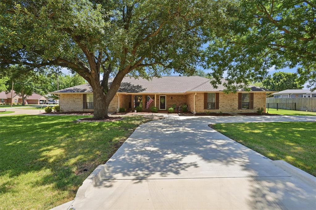 Located on a corner lot shaded by large trees, this home features two circle driveways and a welcoming front porch. Inside, you'll find a wood-burning fireplace in the living area, granite countertops with custom wood cabinets in the kitchen, and a spacious laundry room with pantry storage. Updates include a new roof in 2023, two new water heaters in 2024, kitchen appliances in 2021, a new disposal in 2021, new tile flooring in 2021, luxury wood vinyl flooring in the bedrooms, new storm doors, and HVAC from 2013. The large garage has epoxy flooring with built-in shelving and a workbench. Outside, a storage shed sits in the backyard. Low utility bills round out this well-kept home.