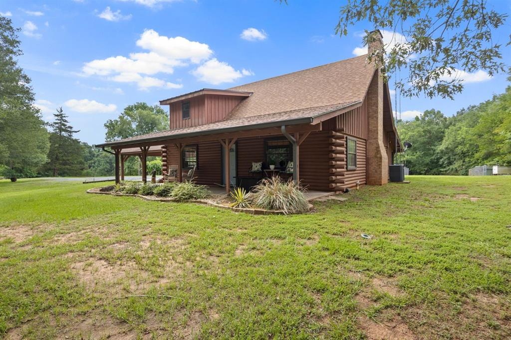 Well-appointed and full of rustic elegance, this beautiful log cabin offers the perfect blend of timeless charm and modern comfort, all in a peaceful setting just minutes from Lake Bob Sandlin, Lake Cypress, Mt. Pleasant, and Mt. Vernon. With 3 bedrooms and 2 updated baths, this inviting home is designed for both relaxation and everyday living. The spacious open great room welcomes you with a soaring vaulted wood ceiling and a dramatic floor-to-ceiling mason stone fireplace that serves as the stunning centerpiece of the home, complete with a gorgeous cypress log mantel that adds warmth and character. Luxury vinyl and wood-look tile flow throughout the downstairs, creating both style and durability. The beautifully updated kitchen is a standout, featuring a farmhouse sink, abundant cabinet space, and a walk-in pantry that offers exceptional storage. Each bathroom has been tastefully updated with modern finishes, while the upstairs bedroom provides a private retreat with its own vaulted ceiling and oversized walk-in closet with built-ins. A versatile mudroom adds even more functionality and can easily serve as a home office, hobby room, or flex space if all bedrooms are in use. Adding to the home’s appeal is the picturesque view of the neighboring pond, creating the perfect backdrop for peaceful mornings with coffee or relaxing evenings. Whether you are looking for a full-time residence, a weekend getaway, or a special place near the lakes, this one-of-a-kind property offers comfort, beauty, and location in one unforgettable package. This is truly a special place to call home.