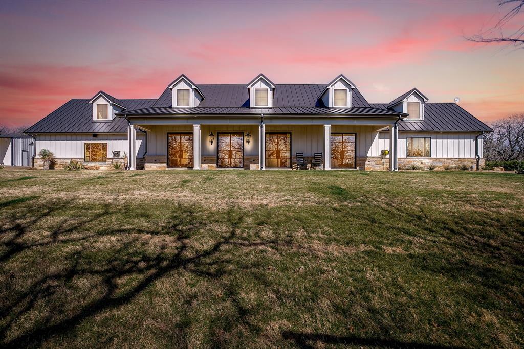 Custom built in 2022 and privately positioned on 10.56 pristine acres in Joshua ISD, 608 CR 914 is a rare modern ranch estate designed for those who value privacy, performance, and refined Texas living.
Spanning 4,119 square feet, this 3-bedroom residence with 3 full baths and 2 half baths blends architectural strength with elevated design. Traditional hardwood floors, marble accents, and three fireplaces create warmth and sophistication throughout.
The chef’s kitchen is a true showpiece, featuring a Wolf double-oven range, Sub-Zero refrigeration, wine fridge, refrigerator drawers, nugget ice maker, warming drawers, commercial vent hood, pot filler, marble countertops, and a fully appointed butler’s pantry — designed for seamless entertaining.
The primary suite offers spa-level comfort with a steam shower and marble finishes, while high-performance construction including spray-foam encapsulation, dual 18 SEER HVAC systems, whole-home filtration, reverse osmosis system, and a whole-home generator ensures effortless living.
A 750 foot deep water well with 5,000-gallon storage and dual booster pumps supports full-property irrigation and the estate’s one-acre stocked pond. Outdoors, enjoy a renovated saltwater pool, crushed granite walkways, extensive hardscape, mature oaks, wood-fired sauna, multiple firepit gathering areas, and curated seating throughout the grounds.
Four spray-foamed outbuildings include a 55x60 show-quality shop with built-in apartment, additional shops, and a 50-amp RV carport — offering versatility for collectors, hobbyists, or multi-generational living. Ag-exempt for cattle.
Offered fully furnished with curated high-end pieces, this estate delivers a truly turnkey experience.
And yes  Shrek, the resident buffalo, conveys with the property.