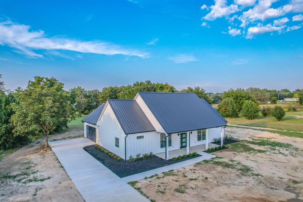 Completed in September 2025, this brand-new custom home showcases exceptional craftsmanship, modern efficiency, and timeless comfort. Set on 2 serene acres with approximately 190 feet of frontage along quiet Country Lane, the property offers a peaceful country setting just minutes from schools, shopping, and the recreational beauty of Cedar Creek Lake. The 1,924 sq. ft. interior is thoughtfully designed for everyday living and entertaining, complemented by expansive outdoor spaces—a 271 sq. ft. front porch, a 410 sq. ft. back porch, and a 574 sq. ft. garage that is fully insulated, heated, and cooled. Built with durability in mind, the home features board-and-batten smart siding with zip-board sheathing, a commercial-grade 26-gauge R-panel metal roof, and seamless gutters for long-lasting performance. Energy efficiency is at the forefront with open-cell spray foam insulation (4” in walls, 6” in ceilings), insulated garage door, and energy-efficient double-hung windows. The foundation boasts 18-inch beams with a 4-inch slab for superior strength. Inside, high-end finishes include custom cultured marble in the bathrooms, marble countertops in the kitchen, laundry, and outdoor kitchen, plus a full suite of GE stainless steel appliances. For modern convenience, the home is pre-wired for security cameras, internet, and a whole-home stereo system. Additional upgrades include a brand-new aerobic septic system installed by Weaver Excavating, along with City of Malakoff water and trash service. For those needing more space, an additional 2 acres are available, featuring a versatile metal shop complete with its own septic system, bathroom, and climate control—perfect for a workshop, business, or guest accommodations. Every detail of this property reflects quality, comfort, and thoughtful design, making it a rare turnkey opportunity in Malakoff ISD.