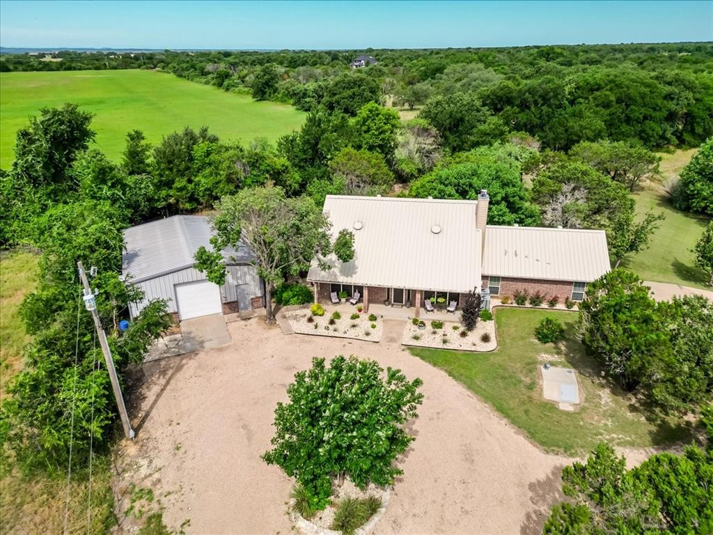 Tucked away among mature trees and completely hidden from the roadway, this custom-built property offers the perfect blend of privacy, functionality, and country living, all with no city taxes! Located near Wheeler Branch in highly desirable Glen Rose, you'll enjoy peaceful seclusion while remaining just minutes from shopping, dining, entertainment, and local attractions including Fossil Rim, Dinosaur Valley State Park, Big Rocks, and only an hour from Fort Worth. The thoughtfully designed custom home features 3 bedrooms, 2.5 bathrooms, an oversized garage, large closets, abundant storage, and extra insulation for exceptional energy efficiency. The spacious kitchen is a chef's dream with granite countertops, a 5-burner cooktop, double ovens, built-in microwave, two pantries, custom cabinetry, and custom blinds throughout. Gather around the cozy wood-burning stove, creating the perfect atmosphere year-round. A standout feature of this property is the impressive 30x40 workshop complete with an office that is heated and cooled, and has an additional bathroom, 220-volt wiring available in the shop; ideal for hobbies, a home-based business, equipment storage, or serious workshop space. Whether you're looking for a private retreat, room for projects, or simply a beautiful place to call home, this one-of-a-kind property delivers it all.