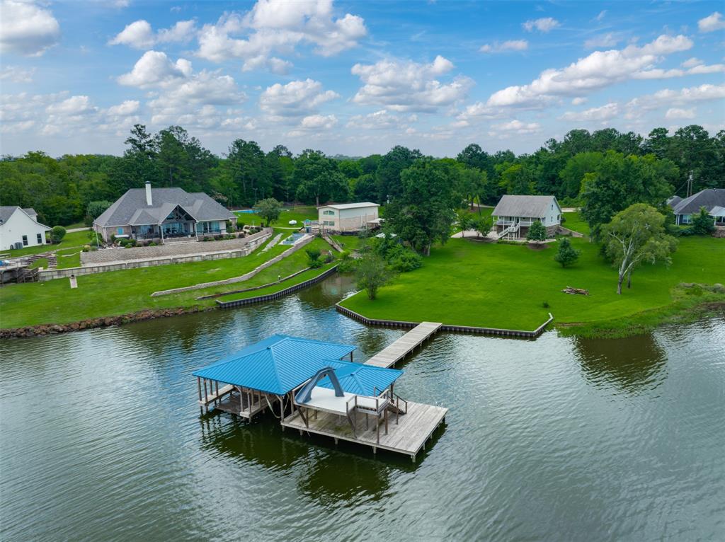 Waterfront home in a highly desirable area on Lake Palestine! Enjoy fishing, boating, and relaxing in the scenic Piney Woods of East Texas—conveniently located just 1.5 hours from Dallas. Built in 2015, this 2,181 sq. ft. home offers 4–5 bedrooms,3.5 bathrooms, and a two-car garage across three well-designed levels. The main floor features the primary suite with an en-suite bath, as well as a utility room for added convenience. The open-concept living, dining, and kitchen area showcases a fireplace, tile flooring, and ample space for entertaining. The kitchen is equipped with a large island and breakfast bar. The upper level includes two bedrooms plus a flexible office or exercise room (or can serve as an additional bedroom), along with a full bath and an additional living area or play area. The lower level features a guest suite or game room with double French doors that open to the back porch, providing easy access to the lake. Outdoor living is a highlight, with a welcoming front porch, a spacious back deck, and a patio overlooking the water—perfect for enjoying lakeside views. The large, level backyard offers plenty of space for volleyball and other outdoor activities. The boathouse is equipped with two lifts for a boat and jet skis as well as a storage room and large covered deck for relaxing by the lake. Situated on a deep-water, protected bay within the well-maintained, site-built home community of Chimney Creek Estates, this property is located on the southeast side of the lake in the desirable Bullard ISD. Schedule a private tour today!