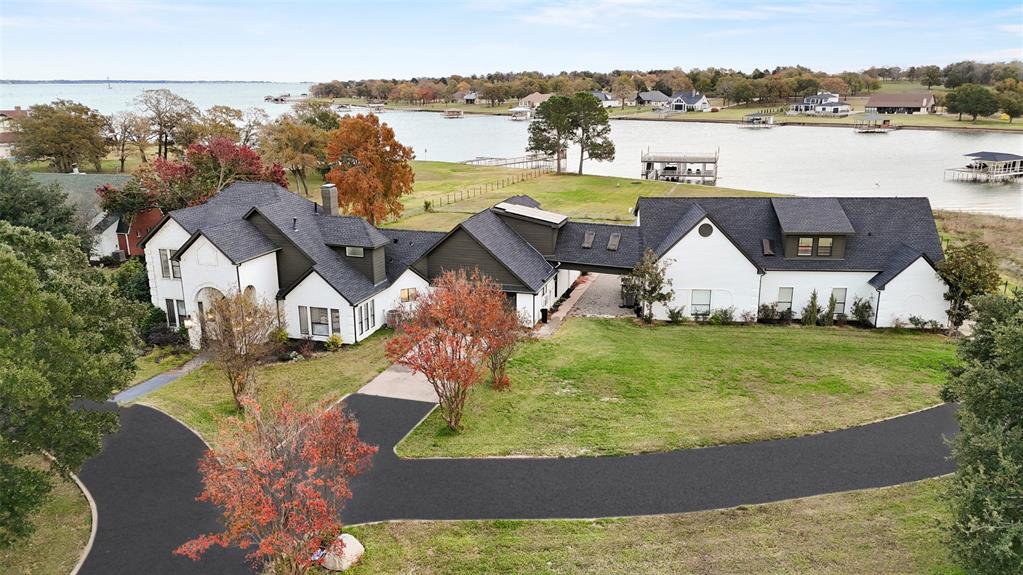 Experience unmatched luxury and waterfront living on 1.9 acres with 275 feet of pristine lake frontage. A double-deck boathouse with two boat slips, jet ski storage, a motorized lift, and unbeatable water access sets the stage for endless recreation. This solar-powered residence spans over 7,000 sq. ft. of thoughtfully designed space, featuring 6 private bedrooms, 9 bathrooms, an office, and an impressive 6-car garage with additional carport. Expansive windows in the living area frame breathtaking lake views, flowing seamlessly into the gourmet kitchen with a large island, Bosch appliances, quartz countertops, and a designer vent hood. The primary suite offers a serene retreat with panoramic views, a spa-like en-suite with soaking tub, walk-in shower, double vanity, and a spacious walk-in closet. Upstairs, enjoy a game room, movie room, additional bedrooms, and two balconies overlooking the lake. Step outside to a covered patio, sprawling backyard, and direct water access—perfect for entertaining or quiet relaxation. Select furniture pieces and watercraft are also available for purchase, providing a turnkey opportunity to embrace lakefront living from day one. This rare property combines privacy, sustainability, luxury, and adventure—offering a one-of-a-kind lakefront lifestyle. Don’t miss your opportunity to call this dream home your own!!