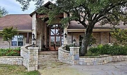 Brazos River views, custom rockwork, and over 5,300 sq ft of one-story living in the sought-after Brazos Heights area of Mineral Wells. Sitting on 1.27 acres in Palo Pinto County, this ranch-style home offers panoramic, unobstructed views of the Brazos River valley from a spacious south-facing back patio. Inside, the home features an open floor plan with 10-foot-plus ceilings, wood and tile flooring, a striking rock fireplace, handcrafted walnut cabinetry, built-ins throughout, and a chef’s kitchen with commercial-grade appliances. The split-bedroom layout includes a spacious primary suite with a large walk-in closet, granite countertops, oversized soaking tub, separate walk-in shower, and private sauna. One Guest Room includes a Murphy Bed with Bookshelves.  Bonus room can serve as a fourth bedroom, office, gym, or hobby space. Features include a game room with rustic antique bar, plantation shutters, solar shades, central vacuum, mudroom, utility room, circular driveway, rear-entry 3-car garage, RV, Boat garage-workshop, covered patio, fenced back yard and peaceful Palo Pinto County views.