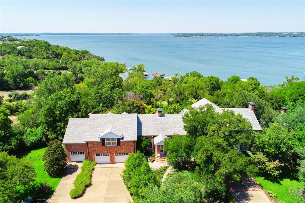 Truly a once in a lifetime opportunity on Eagle Mountain Lake! Hidden away at the end of a gated private drive, this architectural masterpiece sets upon over 9.5 meticulously manicured acres, offering a haven of privacy and tranquility. Approximately 400' of water frontage, with a private beach & boat ramp, 2 separate boat docks, expansive gardens, tennis court, guest cottage, & enchanting mature trees. Designed with both intimacy and grandeur in mind, the property is made for living & entertaining on a grand scale. Breath-taking vaulted ceilings with a double sided floor-to-ceiling limestone fireplace are surrounded by walls of windows, providing uninterrupted panoramic views of the lake and magical gardens. The chef's kitchen is equipped with state-of-the-art stainless steel appliances, bespoke cabinetry, and a sprawling center island. A private master wing boasts separate bathrooms, a fireplace and gorgeous terrace. In this lakeside paradise, a truly extraordinary lifestyle awaits.