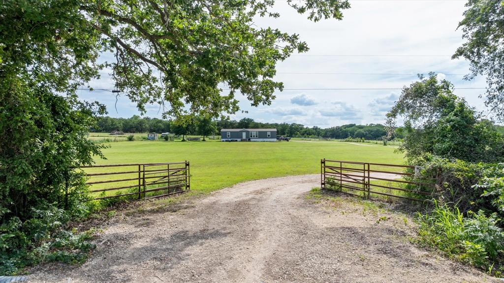 Located on approximately 3 acres just outside Hico, this 2022 home offers 3 bedrooms, 2.5 baths, and a dedicated office. The open-concept floor plan features a spacious living area that flows into a kitchen with an oversized center island, farmhouse sink, abundant cabinetry, and generous counter space. Large windows provide natural light throughout the home. The primary suite includes dual vanities, a soaking tub, separate shower, and ample storage. Two additional bedrooms and a dedicated office provide flexibility for a variety of needs. The manufactured home was installed in 2022 and offers modern finishes and a functional layout. Outside, the property includes fenced areas, a chicken coop, storage buildings, and open space suitable for gardening, livestock projects, or other agricultural and recreational uses. A long driveway provides access to the home and improvements. Additional adjoining acreage is available for purchase. Conveniently located between Hico and Stephenville with easy access to area shopping, dining, schools, and amenities.