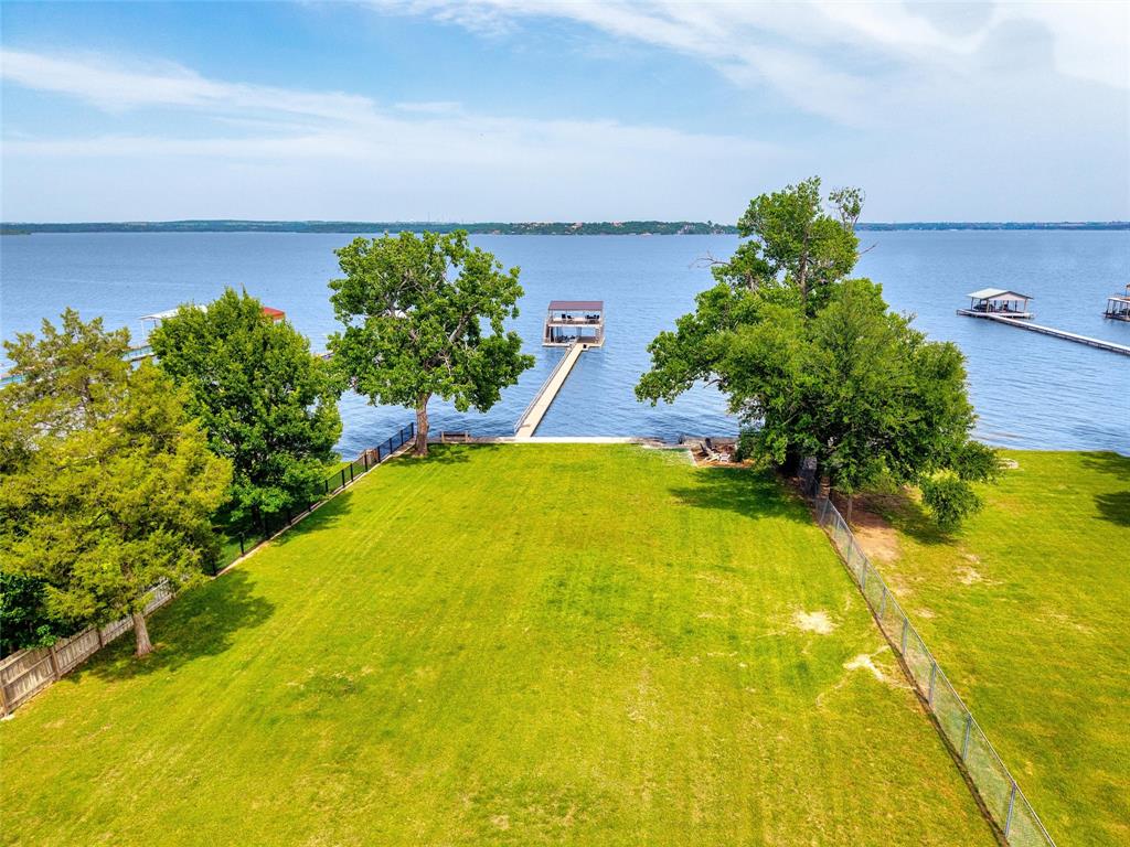 Come play now, build later, and fall in love with lake life every single day at Eagle Mountain Lake.

This 1.1-acre premier lakefront lot isn’t just a place to build—it’s your front-row seat to wide-open water, breathtaking sunrises, and endless weekends on the lake. With 100 feet of prime main-body frontage, you’ll enjoy big water views, cool breezes, and instant access to boating, fishing, and swimming right from your backyard.

The fun starts the moment you arrive—no waiting required. With over $700K in improvements already in place, this property is fully set up for lake days and sunset nights:

Two-story boathouse & dock (approx. 30x30) ready for all your toys
Concrete retaining wall & lakeside sidewalk with steps to the water
Firepit lounge area perfect for stories, s’mores, and starry nights
Lake-fed sprinkler system to keep everything green and gorgeous
Landscaped, fenced, and gated for privacy
Water depth at the end of the boathouse is approximately 10 feet at conservation level

Bring your friends, tie up the boat, cast a line, and soak in the good life while you design and build your dream lake home at your own pace.

Want even more space or a multi-generational setup? The neighboring home at 218 N Broadway is also available (MLS 21174793), creating a rare chance to own a larger slice of this incredible shoreline.

You’re just a quick boat ride from the renowned Fort Worth Boat Club and under 30 minutes to downtown Fort Worth—making it easy to balance peaceful lake living with city convenience.  Close to shopping, hospital and fire department (great for your insurance rates)

Build your dream. Live the lifestyle. Start making lake memories now.