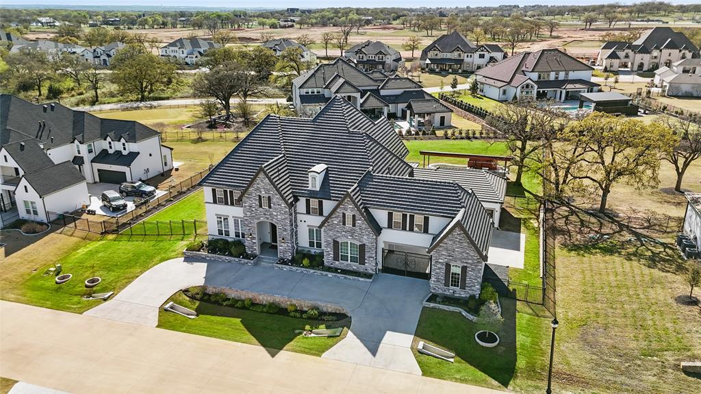 STUNNING TOLL BROTHERS MASTERPIECE ON OVER HALF AN ACRE WITH LUXURY, HEATED COCKTAIL POOL & OUTDOOR KITCHEN! 4 CAR GARAGE! ***SELLER WILL CONSIDER CONCESSIONS TOWARDS CLOSING COSTS, RATE BUY-DOWN OR DISCOUNT PTS!*** Exquisite estate where LUXURY meets COMFORT. Double iron doors lead to an impressive 2-STORY foyer with a graceful, curved staircase & a dedicated study with custom built-ins. Spacious main living area featuring vaulted ceilings, wood beams, floor to ceiling stone fireplace & retractable glass doors for indoor-outdoor living. The kitchen is a culinary paradise designed featuring HIGH-GRADE appliances, a massive marble island, butler's pantry + walk-in pantry. It’s as functional as it is beautiful! Adjoining breakfast room has retractable glass doors, a full-size wine fridge & a 2nd butler's pantry. The primary suite is a spacious sanctuary with a luxurious en-suite bath with soaking tub, spa-like shower, dual sinks & custom WIC. Private guest suite with full bath on main level. 2ND curved staircase leads to 3 add'l bedrooms, each thoughtfully designed with its own ensuite bath for ultimate convenience & comfort. Also upstairs is a 2nd living room, sound-proof media room & a bonus room. Outdoor oasis where you can indulge in the ultimate relaxation experience in your luxurious cocktail pool, complete with jets, lights & heated for year-round enjoyment. Outdoor kitchen, living space & gas firepit. The electric iron gate leads to a motor court with an over-sized 3-car + a separate 4TH car garage. Tons of storage! Tile roof + designer upgrades throughout. EXEMPLARY FLOWER MOUND SCHOOLS & EXCELLENT LOCATION offers relaxed, SUBURBAN LIVING with all the METROPOLITAN CONVENIENCES. Close to DFW Int’l airport, Lake Grapevine, shopping, dining, entertainment & award-winning schools.