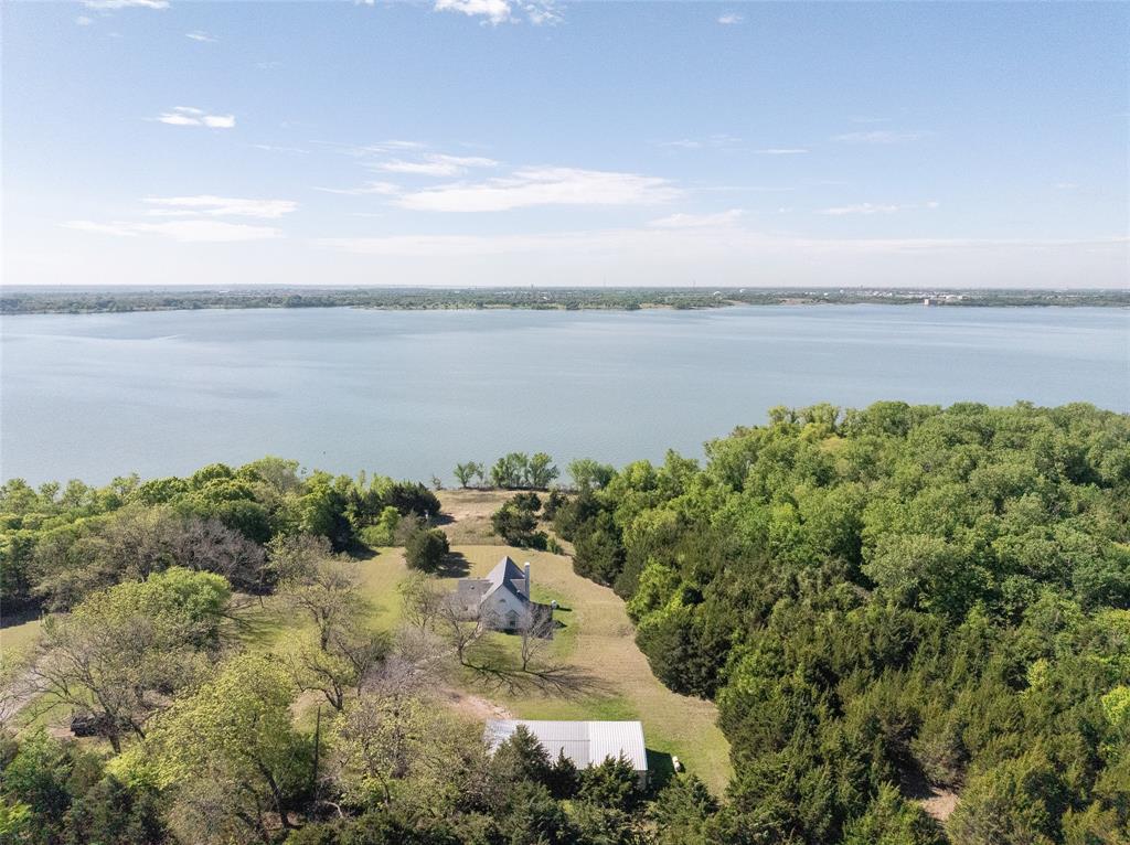 Is there anything better than a lakefront property?  Just take a look at the incredible views this one has...and the corp of engineer property to the south and west will protect the privacy as well! The interior features an open-concept living and kitchen area with large windows oriented toward the lake, providing consistent natural light and unobstructed sightlines to the water. The primary suite and secondary bedrooms are arranged to allow for privacy while maintaining efficient access to shared living areas. Exterior features include a detached garage and dedicated workshop space, suitable for storage, hobbies, or equipment. The surrounding acreage offers a mix of cleared land and mature trees, with a gradual approach to the shoreline.
