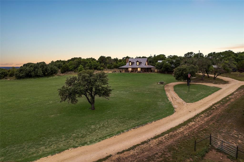Land like this rarely comes to market in Erath County. Twenty-eight years of careful stewardship. Ready to be passed on.
±319.44 contiguous acres on US Highway 281 in Erath County, fourteen miles north of Stephenville and ninety minutes from the Dallas Fort Worth Metroplex. A legacy ranch carved from the historic Jordan Ranch and held by one family for twenty-eight years.
1,570 feet of US Highway 281 frontage with two gated entrances. Elevation rises from 1,090 to 1,260 feet with panoramic views in every direction. Forty-two acres of cleared pasture in Coastal Bermuda and bluestem opens through heavy live oak, post oak, and mesquite timber. A seasonal creek runs through the property. The stretch of 281 in front is locally known as Jordan Hill. The ridge above is Buck Ridge, named for what comes off it.
Two water wells, each 12+ GPM. Three stock tanks, including a spring-fed main.
Whitetail deer, Rio Grande turkey, dove, coyotes, and bobcats. Very low hunting pressure for five years. Two bow stands, one box blind, three feeders in place.
Custom 2,040 sqft home built 2011 by David Taylor Construction. Hill Country ranch style. Stone exterior, standing seam metal roof, slab, 2x6 walls with urethane foam. Three bedrooms, two baths. Mesquite floors on the second level. Custom mesquite and knotty alder doors. Hand-forged iron stair banisters from a Colorado artisan. Dry-stack stone fireplace. Kitchen: quartz counters, custom cabinetry, commercial range, gas appliances, island, walk-in pantry. 1,744 sqft wraparound porch.
Systems: well water with filtration, septic, tankless water heater, 500-gallon in-ground propane, United Cooperative electric. Fiber and Starlink available. Outbuildings: 120 sqft wellhouse (2010), 30 by 30 porte cochère (2024) with 225 sqft of unfinished storage above, 1,248 sqft barn slab (2021).
Active agricultural exemption. No HOA, no subdivision, no restrictions. Morgan Mill ISD and Stephenville High School.