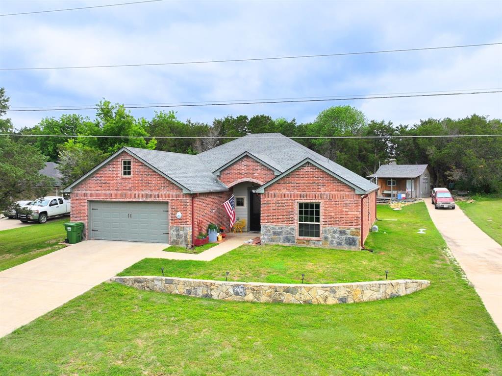 Discover comfort, privacy, and convenience in this charming 3-bedroom, 2-bath home located in the sought-after gated community of Indian Harbor. SELLER IS MOTIVATED, will consider a reasonable offer.  Located on a quiet street and set on half an acre, this property offers room to breathe while still providing quick access to both Granbury’s Historic town center or Glen Rose. Inside, the open-concept layout creates an easy flow between the living, dining, and kitchen areas. The living room features a corner fireplace, perfect for cozy evenings, while the island kitchen offers great workspace and storage. Stained and scored concrete floors add durability and style throughout the main living spaces and makes for easy maintenance. The large primary suite includes a spacious walk-in closet and a comfortable retreat for unwinding. Two additional bedrooms provide flexibility for guests or a home office. Step outside to a large back patio ideal for entertaining or relaxing in your private outdoor space. A shed workshop with AC and electricity adds even more value—perfect for tools, hobbies, or projects. This property blends privacy, functionality, and location in one inviting package.  This is such a terrific house and less than a minute from the front gate for easy ingress and egress.   Indian Harbor boasts lake access, marina, community pool, 24-hour security, gate entrance, and more!