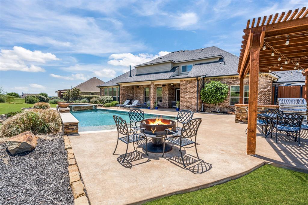 Perched high above the surrounding landscape, this one-of-a-kind custom home captures breathtaking panoramic views from one of the most scenic hilltop settings in the guarded and gated Bella Flora community in Aledo ISD—truly reminiscent of Texas Hill Country living. From sunrise to sunset, enjoy miles of uninterrupted skyline and an elevated vantage point that makes this property exceptionally rare.
Thoughtfully designed for both everyday living and entertaining, the first floor features a spacious primary suite, private guest bedroom, dedicated office, formal dining room, and an open-concept kitchen, breakfast area, and living room—all positioned to maximize natural light and showcase the incredible views. A dry bar and butler’s pantry with a mini refrigerator seamlessly connect the dining room and kitchen, adding both functionality and effortless flow for entertaining.
Upstairs offers two additional bedrooms connected by a Jack-and-Jill bath, a media room, half bath, and a versatile loft-style living area with glass doors opening to a west-facing balcony where you’ll experience unforgettable Texas sunsets and sweeping views for miles.
Designed as a private outdoor retreat, the backyard features a sparkling pool with tanning ledge and bubblers, attached spa, stone waterfall, covered patio with fireplace, and a detached pergola with built-in grill—creating multiple spaces to relax, unwind, or entertain beneath the expansive Texas sky.
Additional interior highlights include hardwood, tile, and carpet flooring, plantation shutters, Cat5 wiring, three zoned HVAC systems, two tankless water heaters, a water storage tank, and two separate garages accommodating up to four vehicles. A new high-impact roof and gutters were installed in May 2025.
A rare opportunity to own a true hilltop property with unmatched views in Bella Flora.