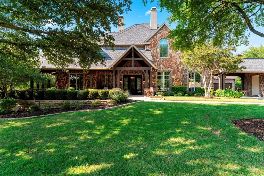 Nestled in one of McKinney’s most exclusive gated communities, this timeless residence offers a perfect blend of elegance, comfort, and luxury. A true private oasis, it seamlessly integrates indoor and outdoor living spaces. The rare wraparound front porch provides a peaceful setting to enjoy views of a nearby pond and fountain. Ideal for relaxing or entertaining, the backyard features a resort-style pool and spa, complemented by an expansive outdoor living area with a built-in grill, refrigerator, fireplace, and TV connection. Surrounded by lush vegetation, the space offers exceptional privacy. Walk thru the front door and the home greets you with a view through to the rear property. To the right, a cozy formal living room with a fireplace flows into the dining room. To the left, a Texas-style home office with double doors leading to a patio with stunning sunset views. The great room, with wood beams on the ceiling and a two-story stone fireplace, overlooks the backyard through large windows that flood the space with light. The chef’s kitchen features a built-in SubZero refrigerator (2025), double ovens, two dishwashers, a gas cooktop, microwave, and a pellet ice maker. A massive island with a separate vegetable sink provides ample meal prep space. The spacious primary suite opens to the backyard and includes a luxurious bath with a jetted tub, separate shower, and custom closet system. Upstairs, a media room and game room are complemented by three bedrooms, each with an en-suite bath. Two oversized garages are accessible via a porte cochere. The home features speakers wired inside and outside of the home, hand-scraped hardwood floors, travertine in the kitchen and breakfast area, and carpeting in the bedrooms. Roman shades and custom draperies elevate the home’s refined atmosphere. This stunning home blends exceptional craftsmanship with modern amenities, offering an unparalleled lifestyle of luxury and privacy in one of McKinney’s most prestigious communities.