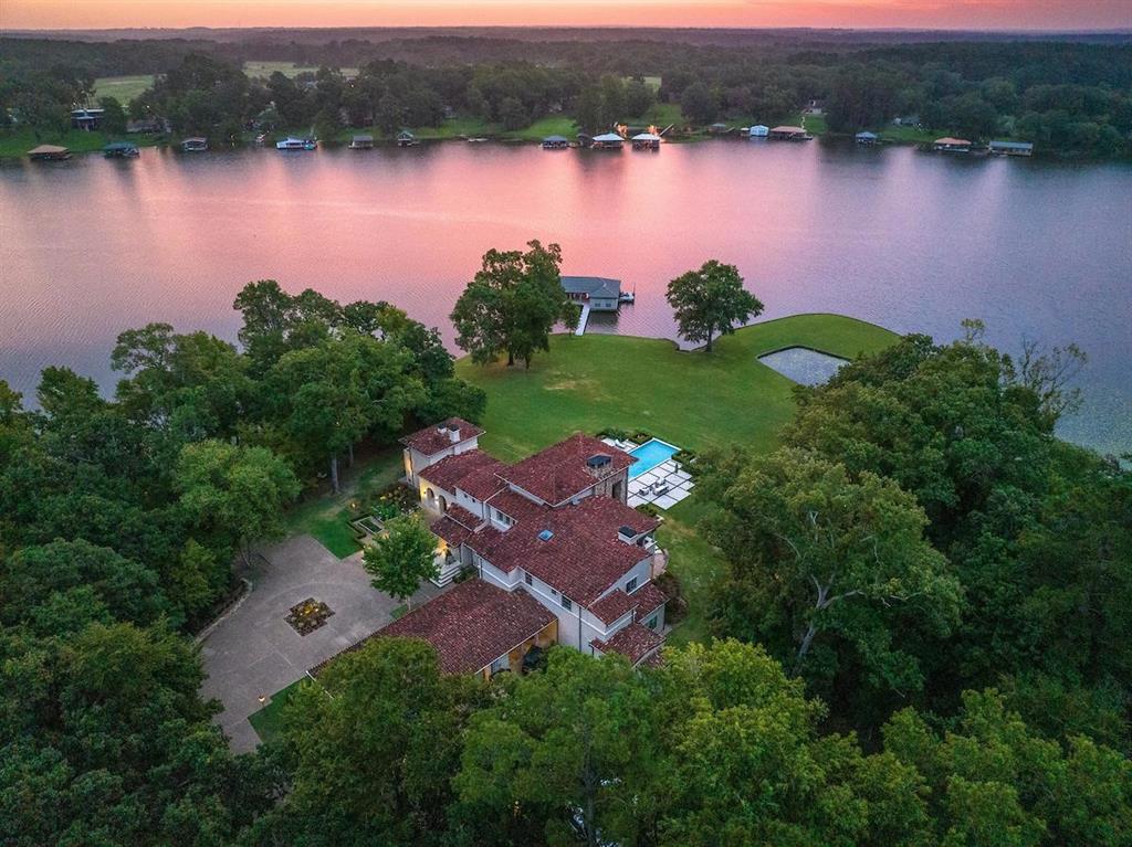 Presenting Peninsula Point, located in the heart of an exclusive enclave on Lake Tyler, this estate with an impressive ~1000 feet of shoreline is set on 3.474+ - acres. The Mediterranean-style residence is accessed through a gated entry, leading to the circular motor court. The home encompasses 6,748 sq. ft. of distinguished living space, the floor plan includes 5 bedrooms, 5 full and 2 half baths across 2 levels, 5 fireplaces, as well as an office, workout room and multiple living areas. The exterior hosts pool, manicured grounds and a covered outdoor living area with refreshment area including sink, grill and fireplace making for a central hub for outdoor gatherings. The boat house offers 3 boat slips and 2 jet ski slips, covered and open lounging spaces and an enclosed kitchen and storage space. With the deepest of water and sweeping views, the lovingly maintained grounds create the experience of the best in lake living just 90 miles east of the Dallas metroplex.