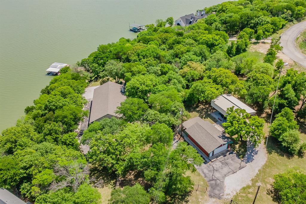 A waterfront paradise awaits on Lake Bridgeport. Tucked away on a private and picturesque 0.88-acre lot in the highly sought-after Cozy Cove on the northside of the lake, this exceptional property features approximately 195 feet of deep-water shoreline, surrounded by mature trees that create a beautiful and one of kind park-like setting.  

This private retreat begins with a pipe-fenced entrance and asphalt driveway, leading to a charming 3-bedroom, 2-bath home offering over 1,800 square feet of living space, plus an additional 600-square-foot enclosed porch—ready for your vision to transform it from cottage-core charm into a modern lakeside escape. A large covered front porch welcomes you, providing the perfect place to relax and enjoy refreshing lake breezes year-round.  Inside, you’ll find a spacious open-concept layout connecting the living room and kitchen, highlighted by a striking corner stone wood-burning fireplace. Abundant built-ins throughout the home offer ample storage. The primary bedroom features an ensuite bath with dual vanities, a separate shower, and a garden soaking tub.  Off the primary bedroom leads to the expansive sunroom.

The property also includes a variety of versatile outbuildings, such as a 12' x 20' accessory structure previously used as a bunkhouse with a sleeping loft and front porch, an 8' x 12' greenhouse, and a 24' x 32' detached garage with an additional 24' x 16' storage area.  Additionally water to the home is supplied by the Grand Harbor water district , which is a real value to have in the area.  No City Taxes, and No HOA!

Completing this impressive offering is a large covered boat dock featuring a boat slip, two jet ski slips, a paddle boat slip, and an additional swim platform—providing everything you need to fully enjoy lakefront living and the many recreational opportunities the lake has to offer.

Lake life awaits—along with the opportunity to create memories that will last a lifetime.