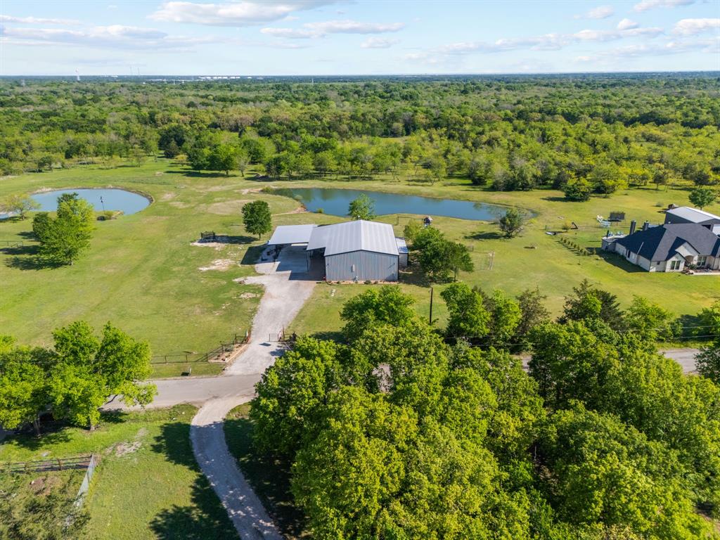 Experience the perfect blend of luxury, functionality, and wide-open Texas beauty just outside the city limits. Caddo Mills ISD! This exceptional 18 acre property is a true retreat, featuring a stunning ¾-acre pond; 20 feet deep and fully stocked with catfish, crappie, bass, and bluegill, creating breathtaking views and endless recreation. Designed with nature and enjoyment in mind, the land includes established trails, seasonal creek beds, and multiple deer stands and feeders tucked among the trees, making it an outdoor lover’s haven. At the heart of the property sits an impressive 50x70 shop and attached barndo that was built in 2023, offering 2,000 square feet of beautifully designed living space with 4 bedrooms and 2 full baths. The first floor showcases an open-concept living area anchored by a show stopping kitchen with a massive center island providing seating for 8+, all positioned to capture panoramic views of the pond and surrounding acreage. Every space is thoughtfully oriented to maximize the scenery and sense of peace. The primary suite is located downstairs, complete with a full bath featuring dual sinks and a walk-in shower with custom double shower heads. Upstairs, a spacious seating area creates the perfect kids’ hangout or secondary living space, along with three additional bedrooms and a full bath. The shop portion is equally impressive, featuring an attached storm shelter and a garage door tall enough to accommodate an RV, with full electric and water hookups both inside the shop and outside under the carport. There’s ample room for an RV, boat, and all your toys! Additional highlights include a separate insulated, climate-controlled dog house with its own fenced yard area, ensuring comfort for every member of the family. This property isn’t just a home—it’s privacy, freedom, and peace. A rare opportunity to own a one-of-a-kind Texas retreat.