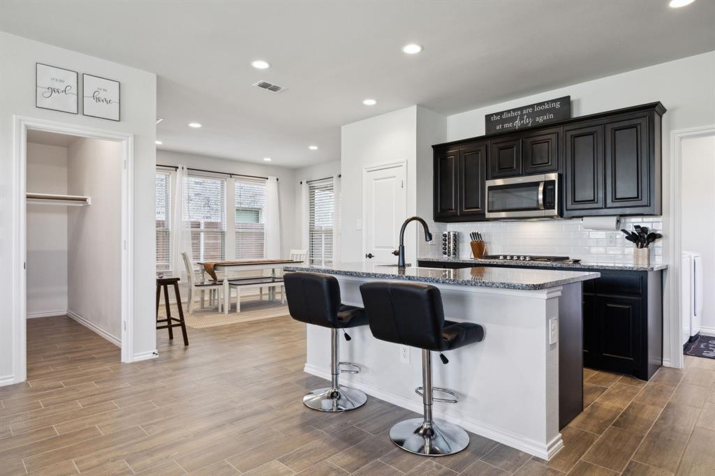 Built by Impression Homes in 2023, this two-story beauty sits on a huge corner lot in the highly sought-after, resort-style community of Solterra in Mesquite—just 11 miles from Downtown Dallas. Comes move-in ready with a washer, dryer, refrigerator, outdoor grill, and more negotiable items, making it easy to settle right in! Featuring an eye-catching stone and brick elevation with a charming front porch, the home boasts wood-look tile flooring, soaring ceilings, and an open-concept design perfect for modern living. Upon your entry into the home your stairway, living room and chef's kitchen come together in perfect harmony. The kitchen shines with a large island with bar seating great for entertaining or watching TV while cooking. Lavish granite countertops, stainless steel appliances, gas cooktop, rich black cabinetry, and a chic white tile backsplash. HGTV ready! Natural light fills the adjoining dining space just before the entrance to the primary suite. The private primary bedroom is tucked away in the back of the home on the first floor. A truly serene retreat! The ensuite bath has dual sinks, huge tiled shower, and a generous walk-in closet. Up the stairs, a versatile loft space for a game room, gym, or second living area. The area is complemented by a full bath separating the two spacious rooms. Enjoy not one, but two quaint backyard spaces! Excellent for outdoor relaxation. Solterra residents enjoy unmatched amenities: a resort-style pool complex, 30-acre lake with kayaking & canoeing, stocked fishing pond, hiking & biking trails, fitness center, dog park, beer garden, and even a treehouse park designed by Animal Planet’s Treehouse Masters. With Mesquite ISD schools nearby and easy highway access, this home blends luxury, comfort, and convenience. Don’t miss the chance to own this like-new gem in one of North Texas’s most exciting communities!