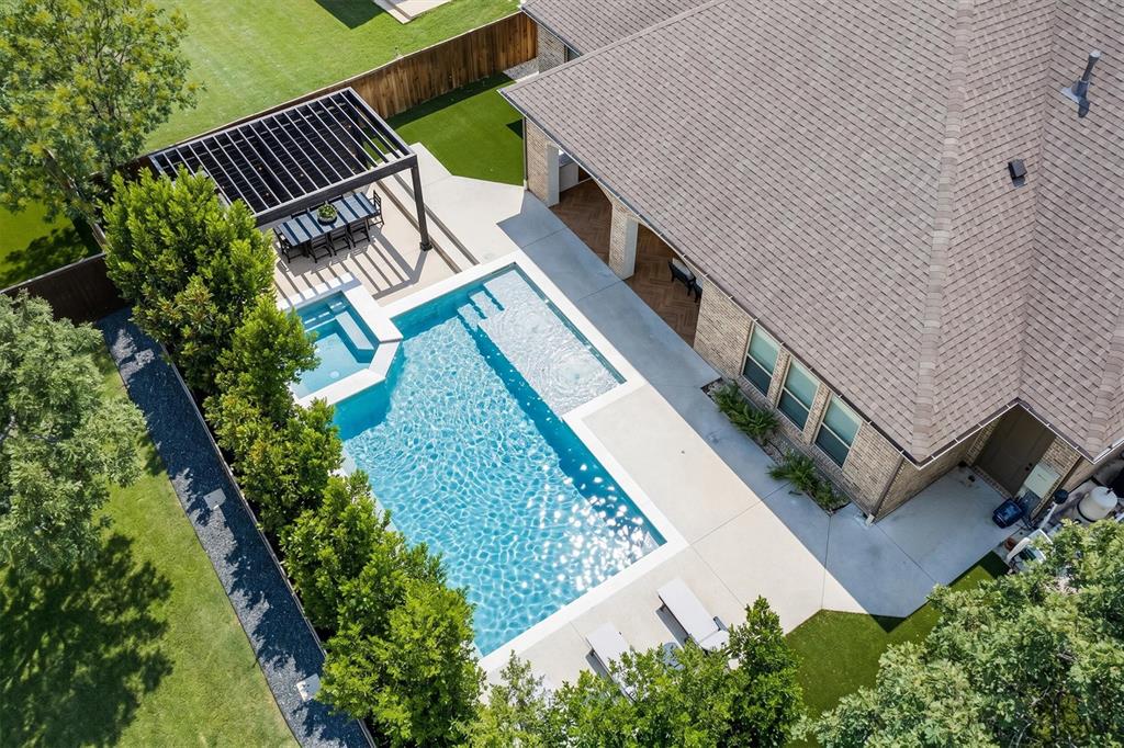RARE opportunity to ASSUME an existing loan at just 2.25%! 417 Boonesville Bend in The Oaks of Argyle, Texas sits in this established neighborhood with mature oak trees, multiple green spaces, trails, and nearby schools. This beautifully built custom home blends timeless design with functional spaces for comfortable everyday living. From the inviting front porch to the sparkling pool and spa, each space feels intentional. Inside, a private office sits just off the entry, offering a quiet place to work or study, while the formal dining room sets the stage for everything from holiday gatherings to intimate dinners. Centered at the heart of the home, the kitchen and family living area open to one another, creating a natural gathering space that feels both inviting and connected. The kitchen is beautifully appointed with a generous island with seating, farmhouse sink, gas cooktop, walk-in pantry, butler’s or coffee bar space, plus a sunlit breakfast nook for everyday moments. A wall of folding glass doors in the family room opens wide, seamlessly connecting to the backyard for year-round enjoyment. The covered patio, built-in grill, outdoor fireplace, lush landscaping, and turf all create a true sense of retreat. The heated pool and oversized spa complete the setting, perfect days and evenings with loved ones and friends. The primary suite is a true escape, featuring a luxurious freestanding bath, a double-headed shower, and separate his and her walk-in closets. A private guest suite on the main level offers comfort and flexibility for visitors or multigenerational living. Upstairs, the home continues to impress with a game room, built-in workspace, and two additional bedrooms each with its own full baths. Balanced, beautiful, and designed for the way you live today, offering privacy and room to grow. Ideally located in the highly regarded Argyle ISD. Perfect blend of small-town charm and modern living just minutes from dining, shopping and major commuter routes.