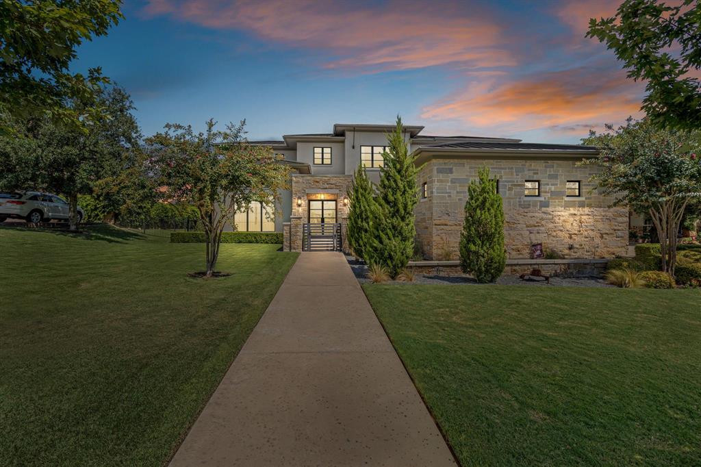 Set on a quiet cul-de-sac in Fort Worth’s prestigious 24-7 gated and guarded Montserrat, this 5-bedroom, 5.5-bath, 5,163 SF residence combines clean architectural design with warm, inviting interiors.

Inside, expansive windows fill the home with natural light, highlighting multiple living areas that create a comfortable yet elegant flow. The chef’s kitchen is a showpiece with custom cabinetry, Wolf range, oversized island with butcher block, and a breakfast area overlooking the pool. A formal dining room is elevated by a dramatic glass-enclosed wine wall.

The great room features wood-beamed ceilings and statement lighting, while an upstairs game room offers additional space for gathering or relaxing. The private primary suite is a true retreat with a spa-inspired bath boasting marble floors, dual vanities, and a walk-in shower. Spacious guest suites provide comfort and privacy for family and visitors alike.

Outdoors, a sleek pool with stone water features, a covered patio with fireplace, and a full outdoor kitchen make entertaining seamless year-round. A private rear gate provides access to neighborhood walking trails, ponds, and playground.

Blending modern transitional design with luxurious finishes and resort-style amenities, 9404 Palencia Court is a premier Montserrat retreat.