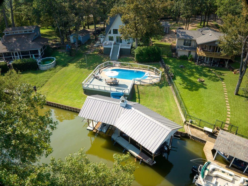 Discover the perfect blend of comfort and lakefront living in this beautifully updated, move-in ready home located on a peaceful private cul-de-sac. Enjoy direct lake access with your own private boat dock and lift, ideal for weekend boating or quiet evenings on the water.  Inside, the home offers a warm, cozy feel with thoughtfully designed spaces, updated finishes, and a layout that makes the most of the view of your own private oasis. The modern kitchen features stylish upgrades and plenty of charm, while the inviting living area is perfect for relaxing or gathering with friends and family.  The upstairs bunk room and guest bath provide a fun and comfortable retreat for children or visitors, giving everyone their own space to relax and enjoy lake life. Step outside to your backyard oasis—a sparkling pool, spacious patio, and tranquil views create a private retreat for year-round enjoyment.  Fully updated and ready for you to move in, this lakefront gem combines modern comfort with cozy charm in a truly special setting.  Pella windows throughout, an outdoor shower and large storage space under the deck are all great additions!!  Don't miss this one!