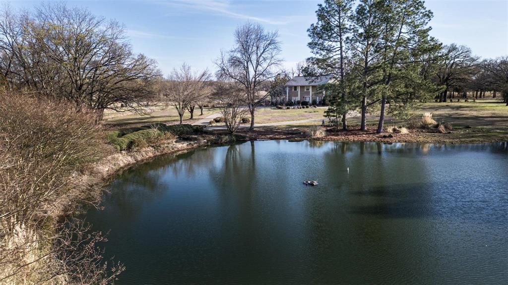 Welcome to an extraordinary 4 acre retreat offering privacy, craftsmanship, and timeless character. There is a long, scenic driveway passing a picturesque pond with a sparkling fountain before arriving at this beautifully crafted two-story residence. Inside, the home showcases extensive woodwork and thoughtful architectural details throughout. The main level features spacious living and entertaining areas and a bedroom with built in bunkbeds.  Staircase leads to an upper landing designed as a cozy library or reading nook. The primary suite is a true sanctuary, opening directly onto a private upstairs balcony with sweeping views of the surrounding acreage. Whether you’re seeking a serene homestead, a weekend escape, or a property with room to expand, this estate offers unmatched potential and natural beauty. Additional 50 acre tracts available, own up to 200 acres! All information is approximate, buyer and buyers agent verify all information.