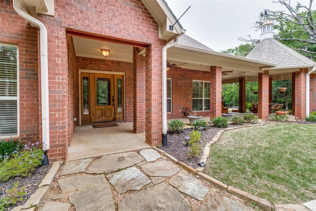 Lake house retreat just minutes from Lake Texoma. This property consists of 2 parcels equaling 3.8 acres and backing to Corp of Engineer land.  This well maintained home offers access to the outdoor patios around the home. The home boasts an open floor plan and slate floors throughout the main living areas. The kitchen is open to the family room and formal dining. The family room features a wood burning fireplace and built in cabinetry. The primary bedroom is spacious with double doors leading out to a side patio with views of the barn. Huge primary bath with garden tub, dual vanities, large separate shower and dual closets. Upstairs are 2 additional bedrooms, full bath and bonus room that could be used as an office or play room. The large covered back patio overlooks a firepit and views of the deer feeder so you may see visiting deer.  There is also a trail that leads through the woods. Secondary lot includes barn. Private well.