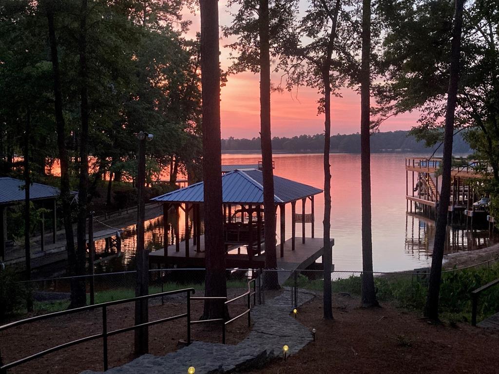 Major Price Improvement due to family relocation needs! Escape to the beauty of East Texas with this waterfront retreat onLake Jacksonville! Situated on a tree shaded lot with an impressive 183' of shoreline, this 3 bedroom, 2 bath home embodiesthe perfect blend of comfort & luxury. The property is fully fenced & secured by gated entrances, ensuring both privacy &peace of mind. A graceful concrete circle drive welcomes you, leading to the entrance of this idyllic lakeside property. The3975 sq. ft. home's recent updates include exterior & interior doors, luxury vinyl plank, windows, completely updatedbathrooms & kitchen, electric panels, light fixtures, roller shade window coverings, water heaters, fresh paint inside & out,gutter guards & new sprinkler system for beautifully landscaped yard, complete with zoysia sod! Step inside & be greeted byrestored brick floors & large great room complete with a gas log fireplace & a captivating wall of windows that showcasebreathtaking views of the serene lake. French doors open to deck lakeside, with the option of a retractable awning. Diningarea & living area are combined for ease of entertaining & enjoyment with friends & family. The beautifully updated kitchenand cozy keeping room w FP are the heart of the home. Indulge in the beauty of nature from the comfort of the sunroom,surrounded by walls of picture windows that bathe the space in natural light while offering vistas of the picturesquelandscape. HUGE master bedroom suite upstairs (can be converted to bunk room) has 3 closets & opens to private deck withamazing lake views. Tons of storage w 2 rooms off garage & walk-in attic. Rain or shine, rest assured knowing that aGenerac generator is ready to provide power, allowing you to relax and enjoy the comforts of home no matter the weather. Aboathouse built in 2021, set back from main lake wave action, provides easy access to fishing, boating, kayaking, & more!Embrace the tranquility lakeside living brings!