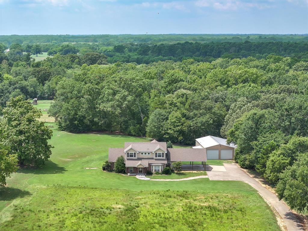 Just 2 miles from Winnsboro in Wood County, this stunning 4-BR-3.5BA home offers the perfect combination of comfort, convenience, & country living. Situated on 5.52 acres of rolling pasture & woods with a stocked pond, the property provides both open space & privacy. The two-story home welcomes you with an expansive den featuring a vaulted ceiling & a WBFP, seamlessly connected to the dining area & gourmet kitchen. The kitchen is designed for both functionality & entertaining, complete with granite countertops, an island, eating bar, gas cooktop, double ovens, serving area, pantry, & generous counter space. The primary suite is located downstairs, highlighted by wood floors & a trey ceiling. The en suite bath includes granite vanities with double sinks, a walk-in shower, jetted tub, & spacious walk-in closet with built-in dressers & shelving. Additional first floor amenities include a home office, large utility room with folding counter & cabinetry & a versatile mudroom-bonus space conveniently located at the carport entry. Upstairs, you’ll find 3 bedrooms. One has a private bath, while the other two share a Jack-and-Jill style bathroom. Outdoor living is a true highlight of this property. A covered 11x21 back patio overlooks the in-ground pool with hot tub spillover. Adjacent to the pool is a fully outfitted outdoor kitchen incorporated into the side of the 30x50 insulated shop complete with a large serving bar & a half bath. The shop features an overhead door for vehicle or equipment storage, & a 10x50 covered lean-to extends from the north side for additional shelter & utility. With an agricultural tax exemption in place, this property offers all the enjoyment of country life with the convenience of being just minutes from town - without city taxes. ::: Substantial painting allowance with acceptable offer. :::