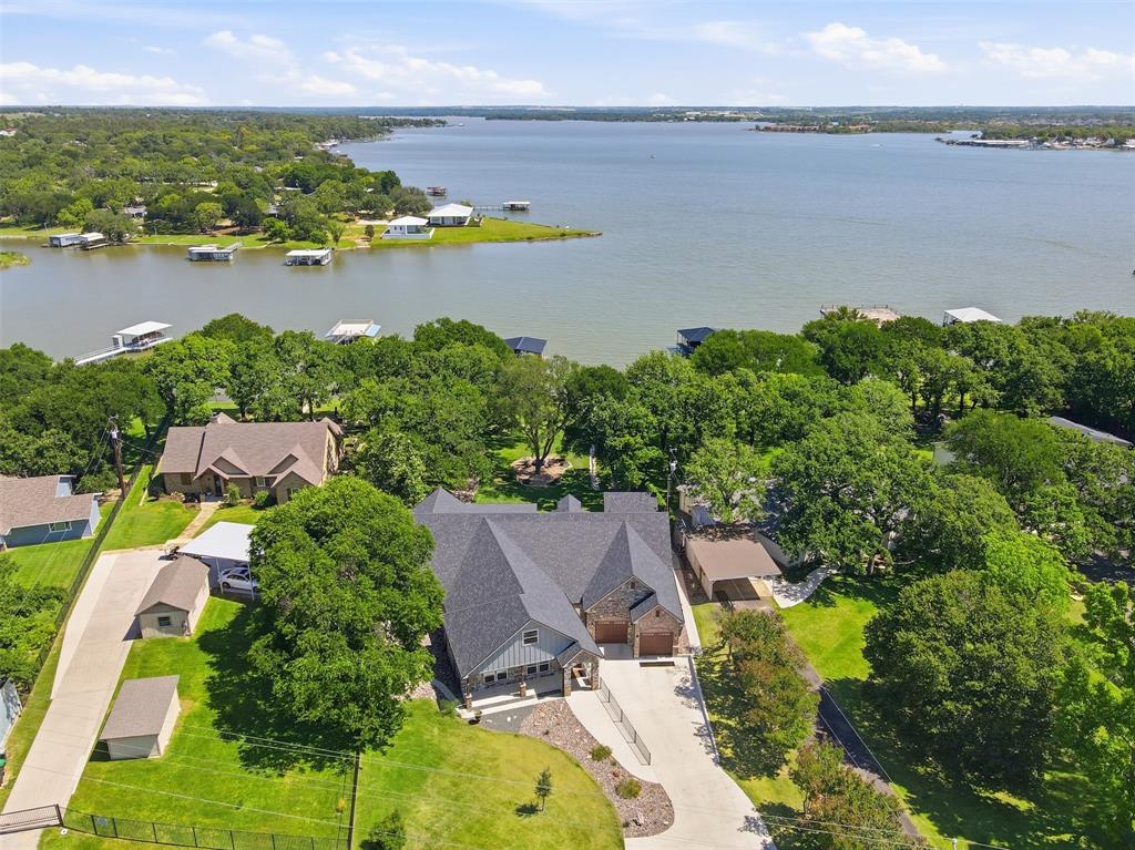 An extraordinary opportunity to own a fully reimagined waterfront estate offering the ultimate in flexibility, privacy, and income potential. Situated on nearly one acre with 172 feet of prime open shoreline, this property delivers it all.  Taken down to the studs and expanded with an additional 1,300 square feet, this home was rebuilt with meticulous attention to detail. The configuration lives like two homes in one, making it ideal for multi-generational living, a corporate retreat, luxury short-term rental, or bed-and-breakfast concept. Inside, you’ll find elevated designer finishes, high-end appliances, and expansive living areas designed to capture stunning water views. A dedicated executive office provides a refined work-from-home environment with privacy and sophistication. The game room is fully equipped—with everything conveying—and furnishings are negotiable, offering the option for a seamless, turn-key experience. Full foam encapsulation ensures impressive energy efficiency and low utility costs year-round. A whole-house water purification system ensures premium water quality at every tap. Step outside to a resort-style setting featuring composite decking boat dock, two jet ski slips, outdoor kitchen for effortless entertaining, full outdoor lake bathroom with private sauna, and spaces designed for gatherings large or small. Private, polished, and built for both relaxation and revenue potential—this Eagle Mountain Lake masterpiece stands in a class of its own.