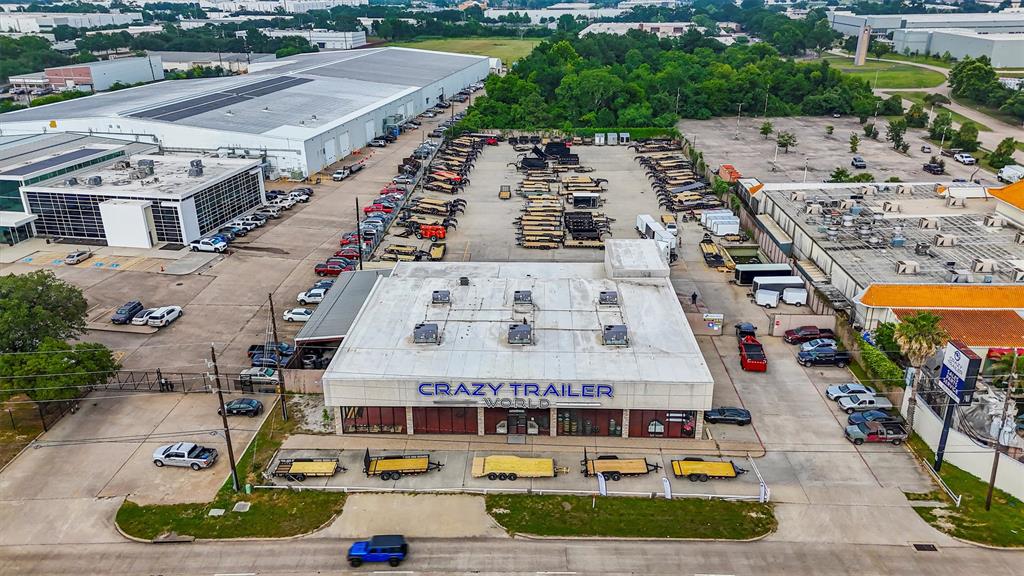 Location, location, location! This 2.64-acre site is strategically positioned along the bustling Interstate 45 (North Freeway) at the northern edge of Houston, Texas, the largest city in the state, with a metropolitan population exceeding 7 million. According to TX-DOT, the average daily traffic count in this area is approximately 260,595 vehicles. The property features two curb cuts, with a driveway directly in front of the I-45 on-ramp, ensuring convenient access.
The improvements on the site are designed to harmonize with the surrounding area through an appealing architectural style. Spanning over 13,500 square feet of gross building area, the facility accommodates a diverse range of uses. The showroom itself encompasses more than 9,335 square feet and is characterized by predominantly glass walls, brick columns, and 22-foot ceilings, making it ideal for showcasing a wide variety of merchandise. A 22-foot door facilitates the efficient movement of inventory in and out of the space, while the building also includes 10 sales offices and a dedicated service center area. Additionally, the property features two mezzanines totaling 1,021 square feet and two public restrooms. At the rear of the building, there is a fully operational shop comprising a 2,226-square-foot heated area, equipped with four bay doors, a restroom, air lines, and ample lighting. The exterior boasts 869 square feet of covered high bay space, complete with a 5-ton overhead crane, as well as 1,328 square feet of low bay space and a 1,767-square-foot canopy along the side of the building, totaling 3,964 square feet of covered areas. The canopy can be easily enclosed should additional building space be required. The entire 2.64 acres is paved with concrete parking, accommodating a variety of vehicles, including cars, boats, trailers, and inventory.  The size, layout, and enhancements of this property provide exceptional versatility, allowing for numerous potential uses.
