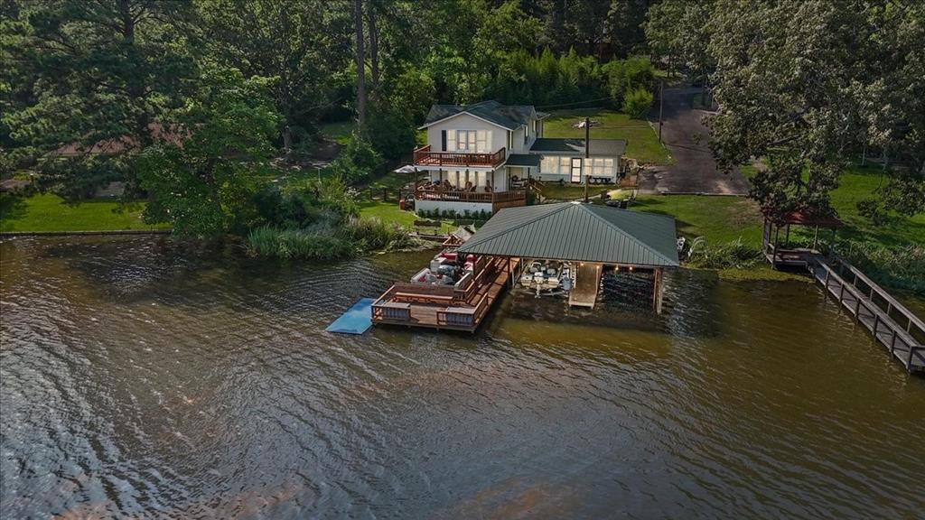 Wonderful rustic waterfront home on lake Lydia nestled along the Texas Dogwood Trail. This secluded, private lake offers serene rolling hills, abundant wildlife, and excellent fishing. Built in 1947, the solid two-story home features 125' of waterfront, original tongue-and-groove walls, upstairs wood plank floors, a large primary suite, two decks, and a spacious eat-in kitchen—ready for your personal touch. Huge covered dock with two boat stalls, lift, storage, and sitting areas. Close to shopping, dining, and with easy access from DFW. Lake Lydia is perfect for boating, fishing and making lifelong memories. New roof and main water line.