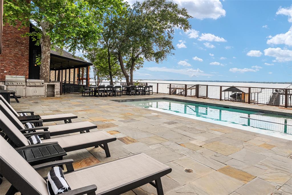 Experience lake living at its finest in this stunning furnished Lakehouse designed for unforgettable gatherings and year-round enjoyment. Spectacular sunsets steal the show each evening, whether you are relaxing on the expansive covered deck or taking in the panoramic views from the second story of the private dock. Every space in this home was thoughtfully designed to maximize comfort, entertainment, and the peaceful beauty of the water. The resort style pool was completed in 2025 and is both heated and chilled, allowing you to enjoy swimming and outdoor living comfortably in every season. Inside, the spacious layout features five bedrooms, including an incredible bunk room with six built in bunks that kids and guests will absolutely love. Adjacent to the upstairs bunk room is a large game and bonus room, creating the perfect entertainment retreat with plenty of room for movies, games, and gathering with friends and family. The second level also offers two additional guest bedrooms along with a convenient second laundry room, making hosting easy and comfortable for everyone. On the main level, you will find the luxurious primary suite, an additional guest room, and another full laundry room for everyday convenience. The heart of the home is the beautifully appointed kitchen, fully equipped for entertaining and complete with a wood burning pizza oven that is always a favorite among family and guests. The kitchen flows seamlessly into the dining area, where a large table seats twelve comfortably, and into the inviting living room featuring a dramatic wall of windows that capture the serene lake views from nearly every angle.
This remarkable property also includes an additional lot directly in front of the home, offering extra space for outdoor activities, future possibilities, or simply preserving the tranquil surroundings. Being sold fully furnished, this Lakehouse is truly move in ready so you can begin making memories at the lake immediately.