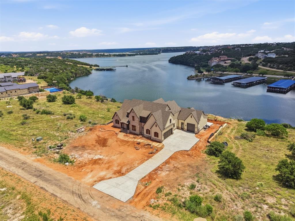 Perched atop the cliffs of highly sought-after Gaines Bend, this exceptional new construction home showcases breathtaking panoramic views of Possum Kingdom Lake and offers the ultimate luxury lake lifestyle. Designed with entertaining and relaxation in mind, the home features 5 spacious bedrooms, 5 bathrooms, and two expansive living areas, providing ample space for hosting family and friends.

The open-concept design is highlighted by soaring ceilings, abundant natural light, and walls of windows that perfectly frame the stunning lake views. The chef-inspired kitchen flows seamlessly into the main living and dining areas, creating an inviting atmosphere for gatherings of any size.

Step outside to experience true resort-style living. A spectacular pool overlooks the lake, while the oversized outdoor entertaining patio provides the perfect setting for enjoying sunsets, hosting guests, or simply taking in the incredible scenery.

Additional features include an attached two-car garage and a dedicated attached boat garage, offering plenty of room for vehicles, watercraft, and lake gear. As an added bonus, the property conveys with a boat slip at the Gaines Bend Private Marina—the largest boat slip available in the marina.

Combining luxury finishes, unmatched views, and premier lake access, this one-of-a-kind property presents a rare opportunity to own a truly remarkable retreat on Possum Kingdom Lake.