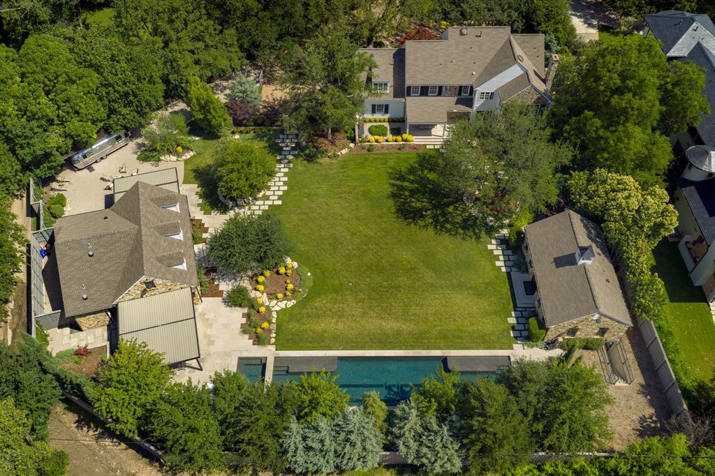 Three structures, one full acre in Preston Hollow, and a single great lawn bringing them together. This isn't merely a house — it's a camp, in the Gilded Age sense of the word. The 4,449-square-foot main residence is only the beginning. Add the pool house and guest cottage and you reach nearly 8,900 air-conditioned square feet — a style of family compound rarely found within city limits. The acre is wedge-shaped, and a fifty-foot setback opens the backyard generously behind the home, so it lives far larger than other one-acre lots nearby. The main residence is the quiet anchor. A comprehensive renovation preserved the warmth of the original architecture while layering in every modern comfort: Lutron lighting, integrated Sonos audio, fully remodeled kitchen and bathrooms. Upstairs belongs to the family, with a serene primary suite, three more bedrooms, and a generous game room. The pool house is built for the way you entertain — intimate enough for a Tuesday-night dinner, equipped for the epic party. Full kitchen, bar, lounge, covered and heated al fresco dining on two sides, with a media room and game room below. Because it stands apart, guests linger without encroaching on your space. Across the lawn, the cottage is a third way to live here, featuring a bedroom suite with a steam shower, wet bar, and flex space, ready to house visiting parents, give an older child independence, or serve as a private office. Outside: a 75-foot lap pool, grounds by Marlin Landscape, a fire pit, and a vintage Airstream that conveys with the property. And for all its seclusion, Inwood Village, Dallas's top private schools, Love Field, and the Park Cities are all minutes away. A private retreat, fully woven into the city you already love.