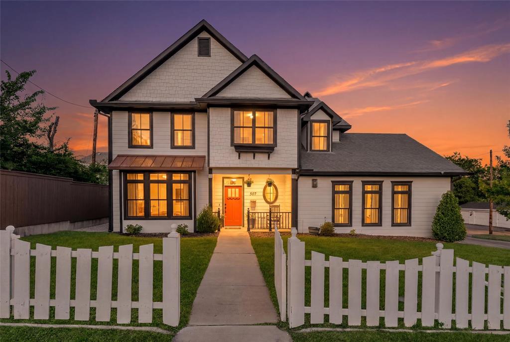 HISTORIC McKINNEY and just a few blocks from the popular Downtown McKinney Square! Built in 2019, this custom British Builder home offers exceptional craftsmanship, thoughtful upgrades, and a flexible five-bedroom floor plan in one of McKinney’s most desirable downtown neighborhoods. Situated on a corner lot behind a classic white picket fence, the home features five bedrooms, including a convenient downstairs secondary bedroom and an upstairs bedroom currently used as a home office. The oversized primary suite is a true retreat with a spacious en suite bath featuring a jetted garden tub. Engineered hardwood floors flow through the main living areas, complemented by Restoration Hardware lighting, solid-core doors, upgraded hardware, a farmhouse sink, premium cabinetry and countertops, and a gas fireplace with a custom carved oak mantel. The beautifully landscaped backyard is designed for relaxing and entertaining, featuring a covered arbor, fire pit, flowering magnolia trees, and Emerald Zoysia lawn. Additional highlights include Marvin fiberglass composite windows and French patio door, a top-of-the-line 25 SEER Lennox zoned HVAC system with air purification, and an oversized 25-foot-deep garage with 9-foot doors designed to accommodate larger vehicles and provide ample storage. All of this just steps from the shopping, dining, entertainment, and year-round events of Historic Downtown McKinney. A rare opportunity to enjoy modern custom construction with the charm and walkability of downtown living.