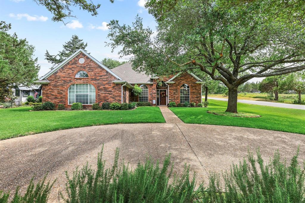 Experience the relaxed lifestyle that makes Tanglewood such a sought-after destination. Located on a beautifully landscaped corner lot in the Fairway Hollow subdivision, this well-maintained brick home offers comfort, convenience, and a prime location just minutes from Lake Texoma and only a short golf cart ride to the nearby golf course.  With 2,284 square feet, 3 bedrooms, and 2.5 bathrooms, the thoughtfully designed floor plan features a spacious living room filled with natural light, crown molding, and a cozy wood-burning fireplace. The open layout flows seamlessly into the kitchen, which offers stainless steel appliances, including the refrigerator, ample cabinetry, generous workspace, and easy access to both the breakfast area and formal dining room.  The private primary suite provides a relaxing retreat with room for a sitting area, a custom walk-in closet with built-in shelving and drawers, and an ensuite bath featuring dual granite-topped vanities, a soaking tub, and an updated walk-in shower.  One of the home's standout features is the backyard oasis. Mature trees, lush St. Augustine grass, a privacy fence, multiple sitting areas, and a covered patio create the perfect setting for entertaining, relaxing, and enjoying beautiful Texas sunsets.  Enjoy the convenience of being near the Tanglewood area, where you'll find popular dining and gathering spots, including the well-known Tower Lounge overlooking Lake Texoma. Combining a desirable location, functional layout, and inviting outdoor spaces, this home offers an exceptional opportunity to enjoy the Lake Texoma lifestyle.
