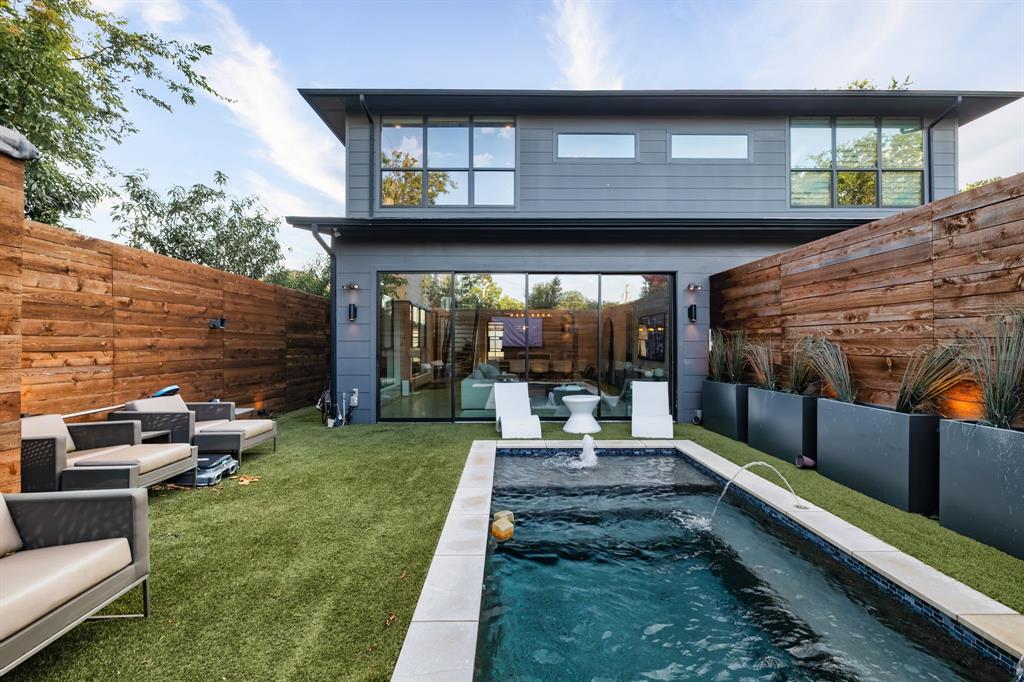 Welcome to sleek modern living in Inwood Park. This Scandinavian-inspired home blends smooth stucco, stained wood, slatted screens and full-view glass garage doors for standout curb appeal. Inside, floor-to-ceiling glass, museum-finish walls, 10-foot ceilings, designer pendants and recessed Hue lighting create a gallery-like vibe over diamond-polished concrete on the main level and hardwoods upstairs. The first floor flows through an open living, dining and kitchen area anchored by a long quartz island, low-profile custom cabinetry, stainless appliances and a Moen smart faucet, while multi-panel sliders open to a private courtyard. A steel-and-wood staircase, chic powder bath and showcase two-car garage complete the level. Upstairs, two ensuite bedrooms are divided by a central loft or study. The primary suite offers a spa bath with dual floating vanities, a large curbless double shower and a custom closet; the guest suite features a freestanding soaking tub. Outdoors, cedar fencing, synthetic turf and architectural planters surround a heated smart pool and spa finished in PebbleTec with deck jets and LED lighting, Sonos audio and a Samsung Terrace weatherproof TV—your private resort minutes from Inwood Park Village, Highland Park Village and Love Field. A fully integrated smart ecosystem elevates daily life with Brilliant touch panels, Control4 integration, Philips Hue and Lutron scenes, and dual-zone Ecobee thermostats. Robust security includes full-perimeter HD cameras (including the alley), pedestrian and front entries with HD video, two-way audio and remote intercom, plus Aqara doorbells. The myQ garage opener adds a built-in camera, remote open and close and alerts. Sonos surround serves the living, kitchen and office; LG Gallery TVs integrate throughout; the primary bath and guest bath include discreet audio; bedrooms add motorized shades and remote fans. Aroma360 luxury HVAC scenting infuses the home. Future-ready, turnkey and unforgettable.